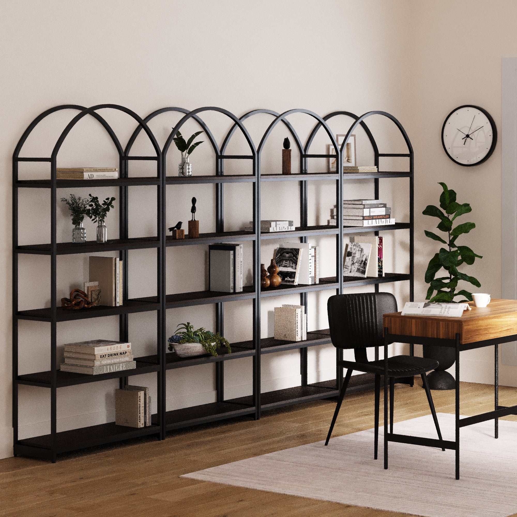A modern home office features the Nathan James Metal 5-Shelf Arched Bookshelves Black (Set of 4), filled with books, plants, and décor. A wooden desk with a black chair sits on a light rug, with a plant and clock on the nearby wall.