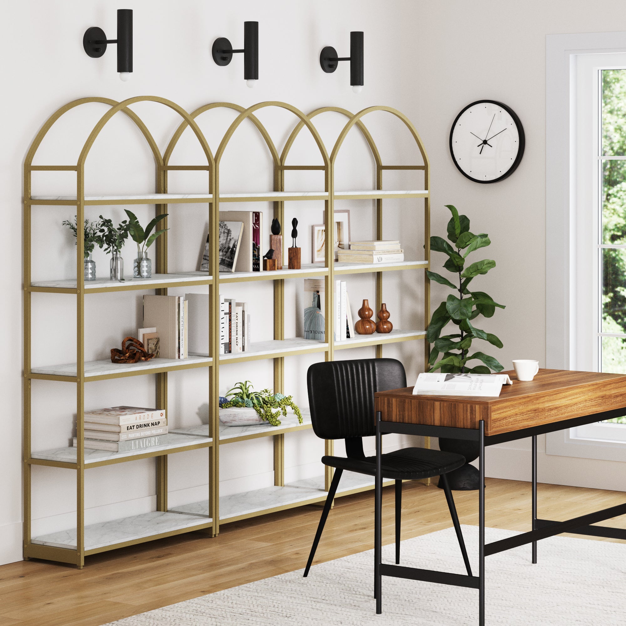 Modern home office with three Nathan James Metal 5-Shelf Arched Bookshelves Gold, styled with various decor items, a wooden desk and black chair, potted plant, wall clock, two windows, and three black wall sconces.