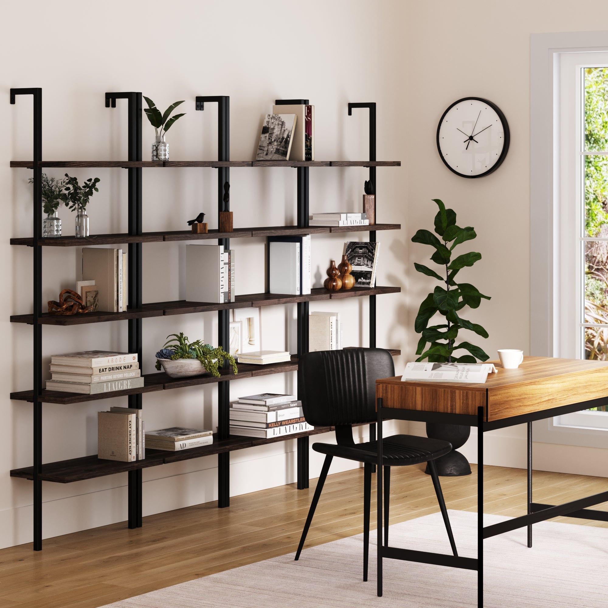 A modern home office features a wooden desk, black chair, and four Nathan James 5-Shelf Ladder Wall Bookshelves in nutmeg, filled with books, plants, and decor. A wall clock and green plant sit near a sunlit window.