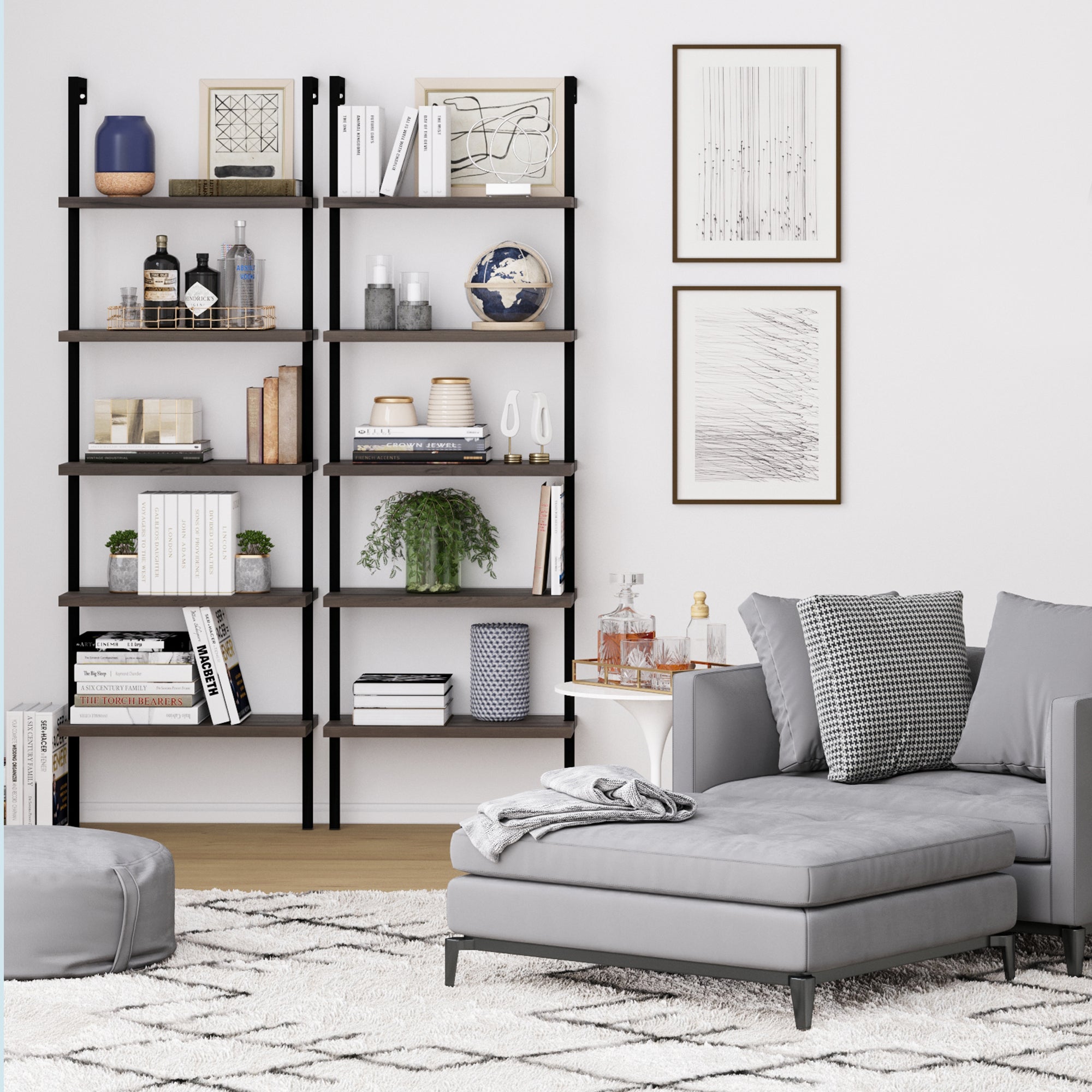 A modern living room with a gray sectional sofa, patterned rug, and a black shelving unit filled with books, plants, decor, and framed art on a white wall. Clear drinkware and a tray sit on a small side table.