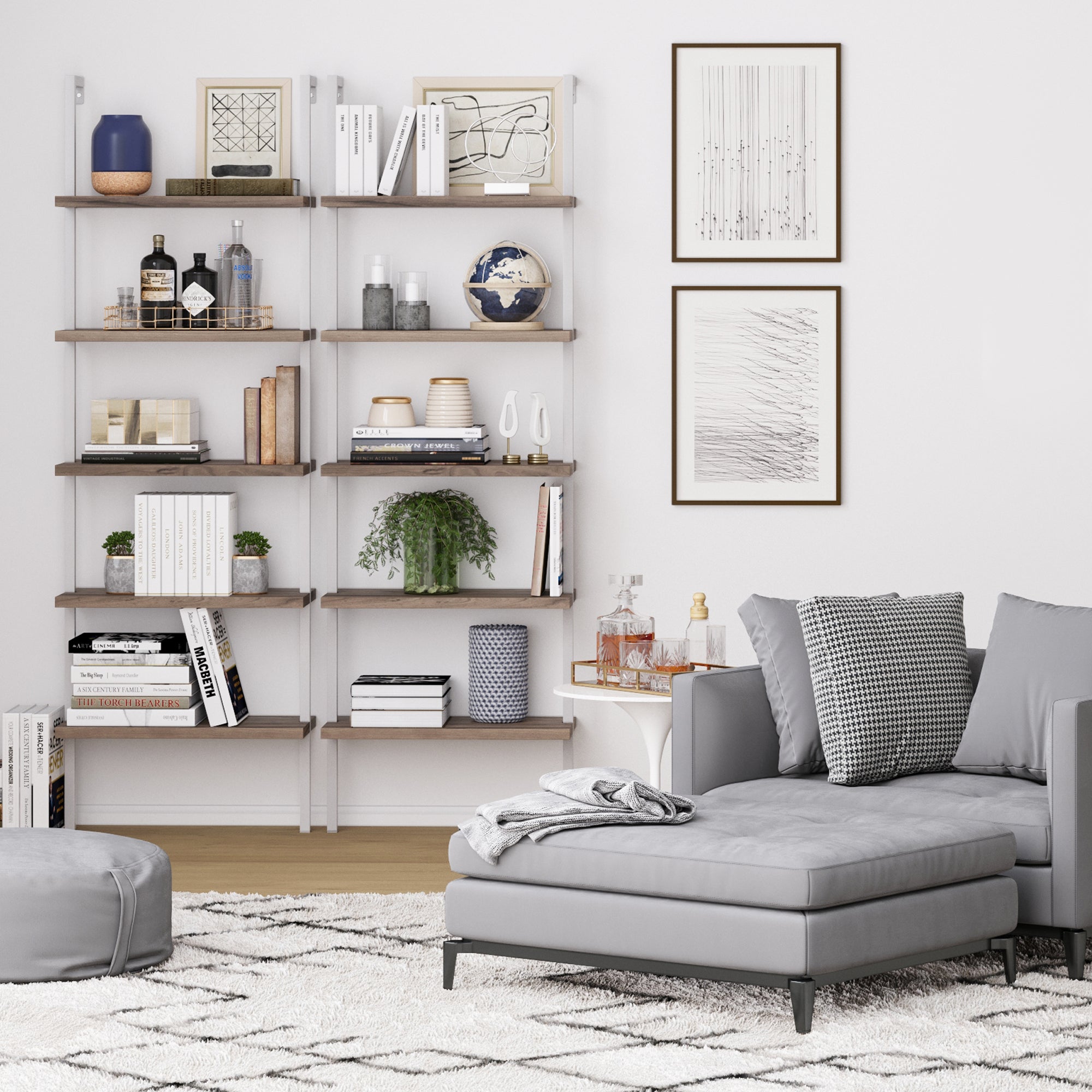 Modern living room with a gray chaise lounge, ottoman, patterned rug, pillows, wall art, and a Nathan James 5-Shelf Ladder Bookshelf in Oak Matte White displaying books, plants, vases, and décor against a white wall.
