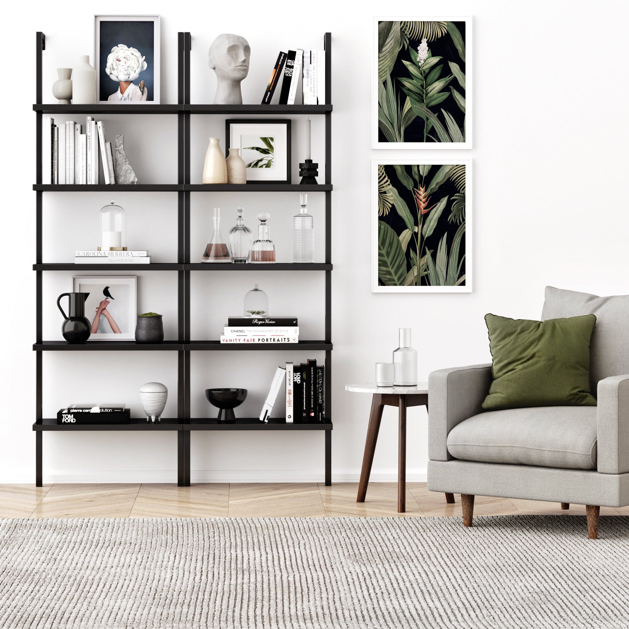 A modern living room with a gray armchair, small side table, and a Nathan James 5-Shelf Ladder Bookshelf in black displaying books, vases, and art; two botanical wall prints and a light rug complete the look on the wooden floor.
