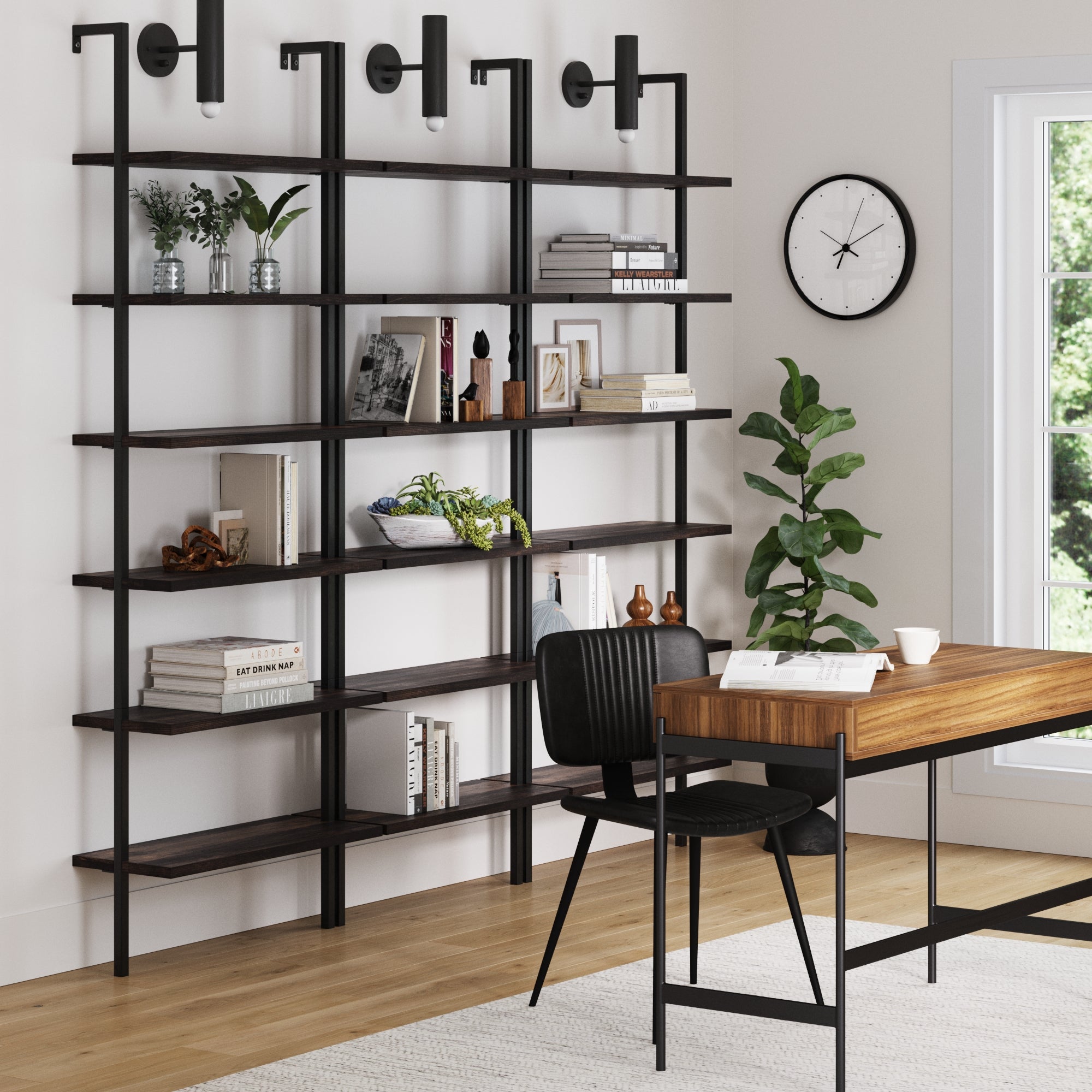 Modern home office featuring a set of three Nathan James 6-Shelf Bookcases in Nutmeg Matte Black, styled with books, plants, decor, a wooden desk and black chair, wall clock, potted plant, and ample natural light from a large window.