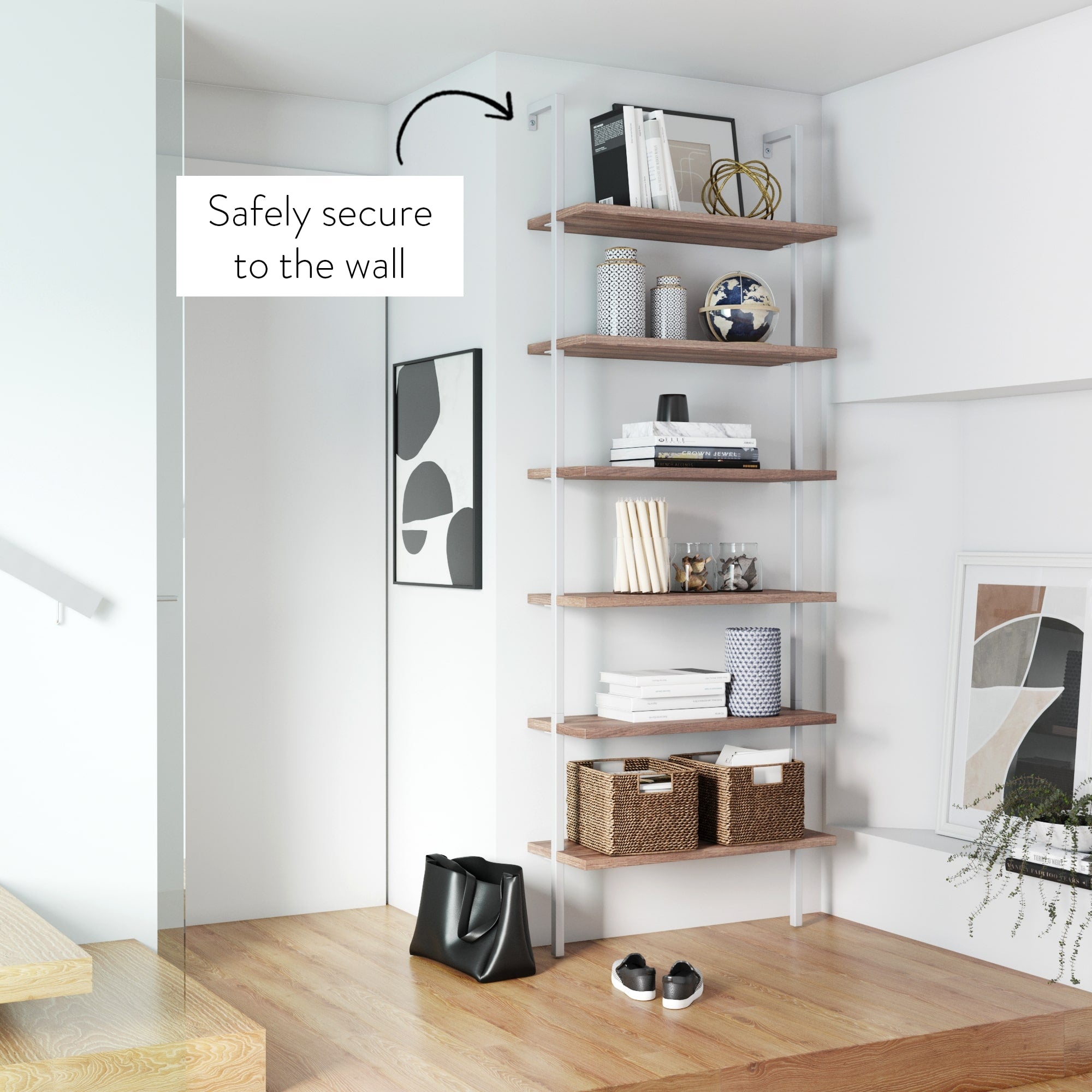 A modern wooden bookshelf with five shelves is secured to a white wall. The shelves display books, baskets, and decorative items. A black bag and shoes are on the wooden floor. Text reads: Safely secure to the wall.