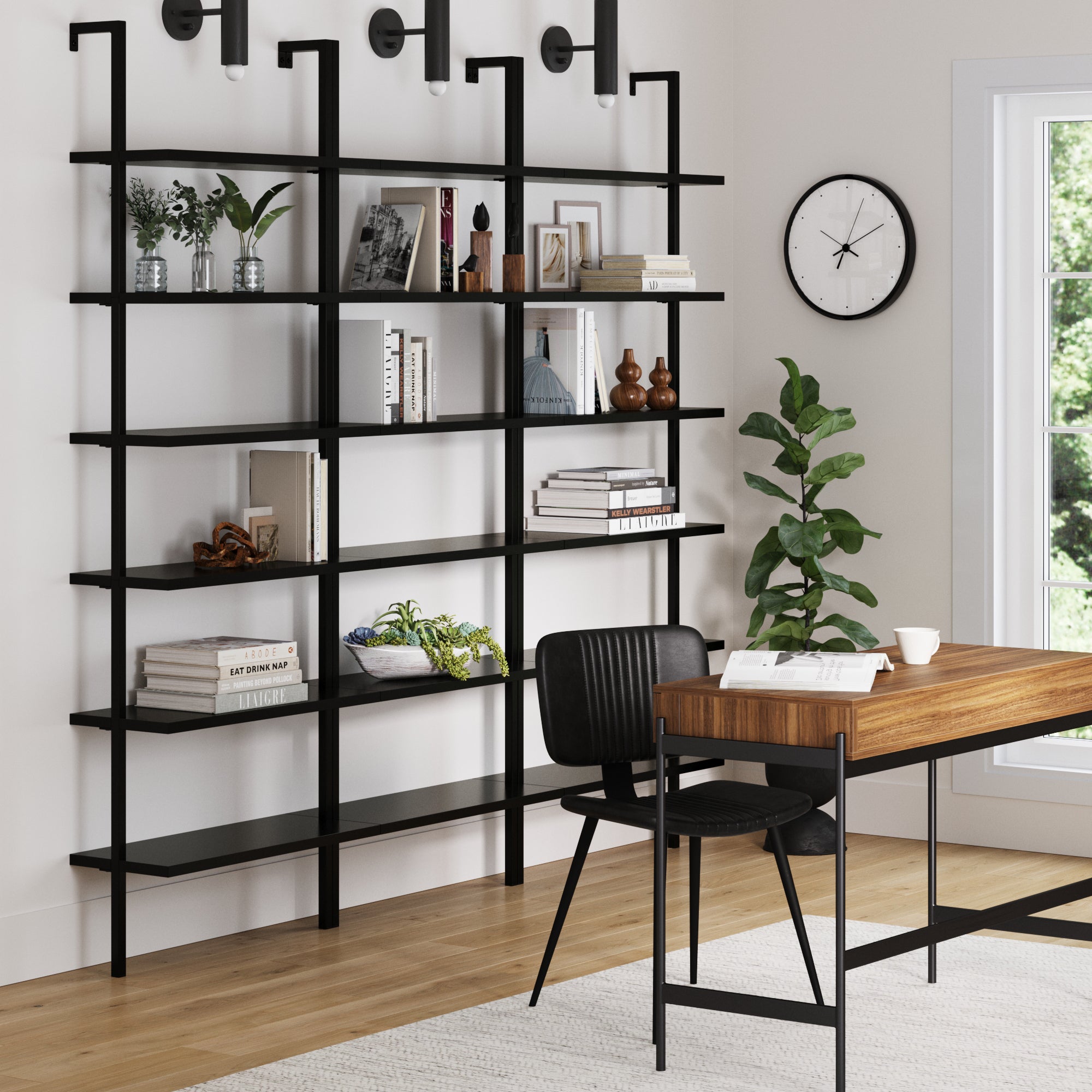 A modern home office featuring the Nathan James 6-Shelf Wall Mount Bookshelf Black (Set of 3), displaying books and decor, plus a wooden desk, black chair, wall clock, potted plant, and a large window with natural light.