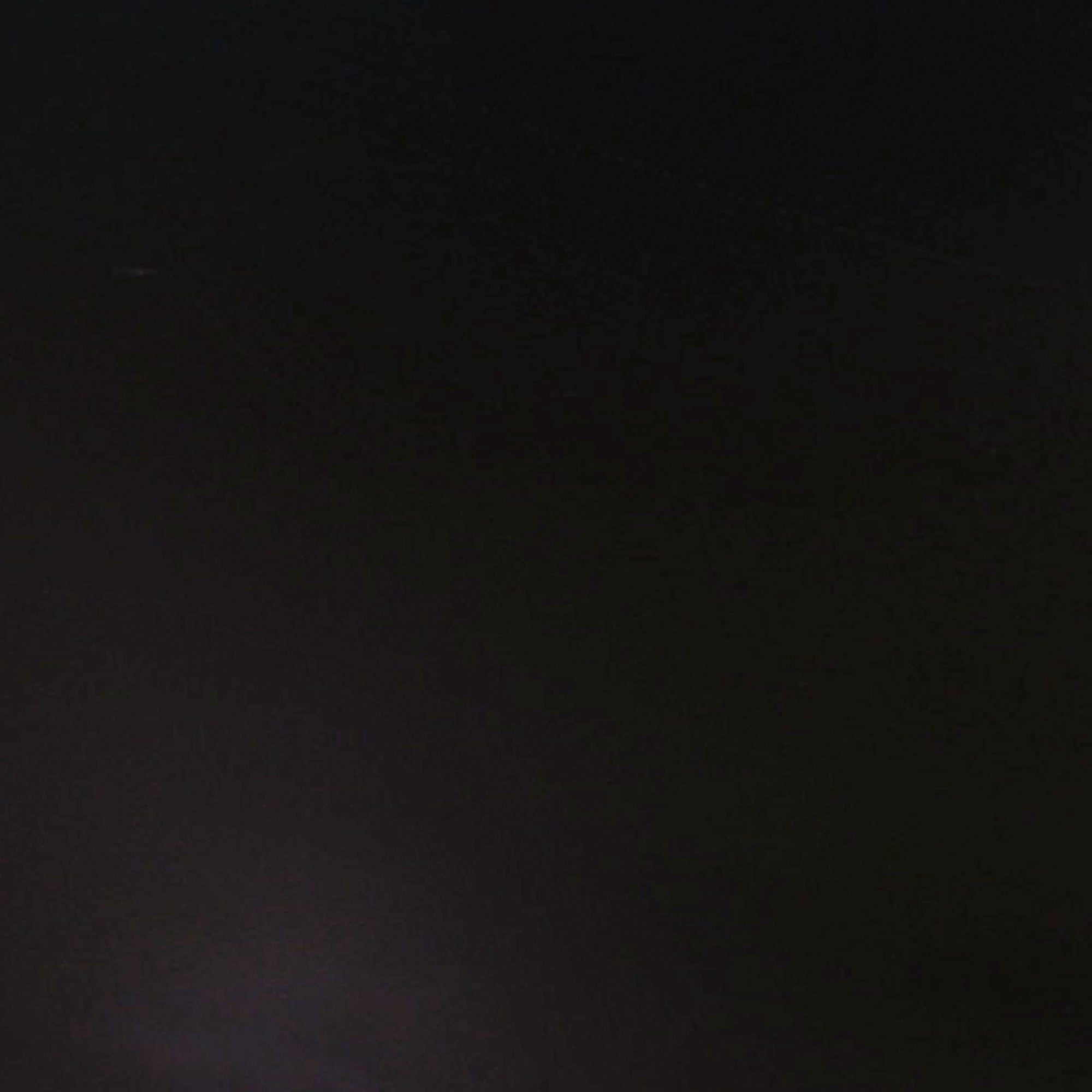 A mostly dark, black image with minimal visible details; there is a faint area of lighter color near the bottom left corner.