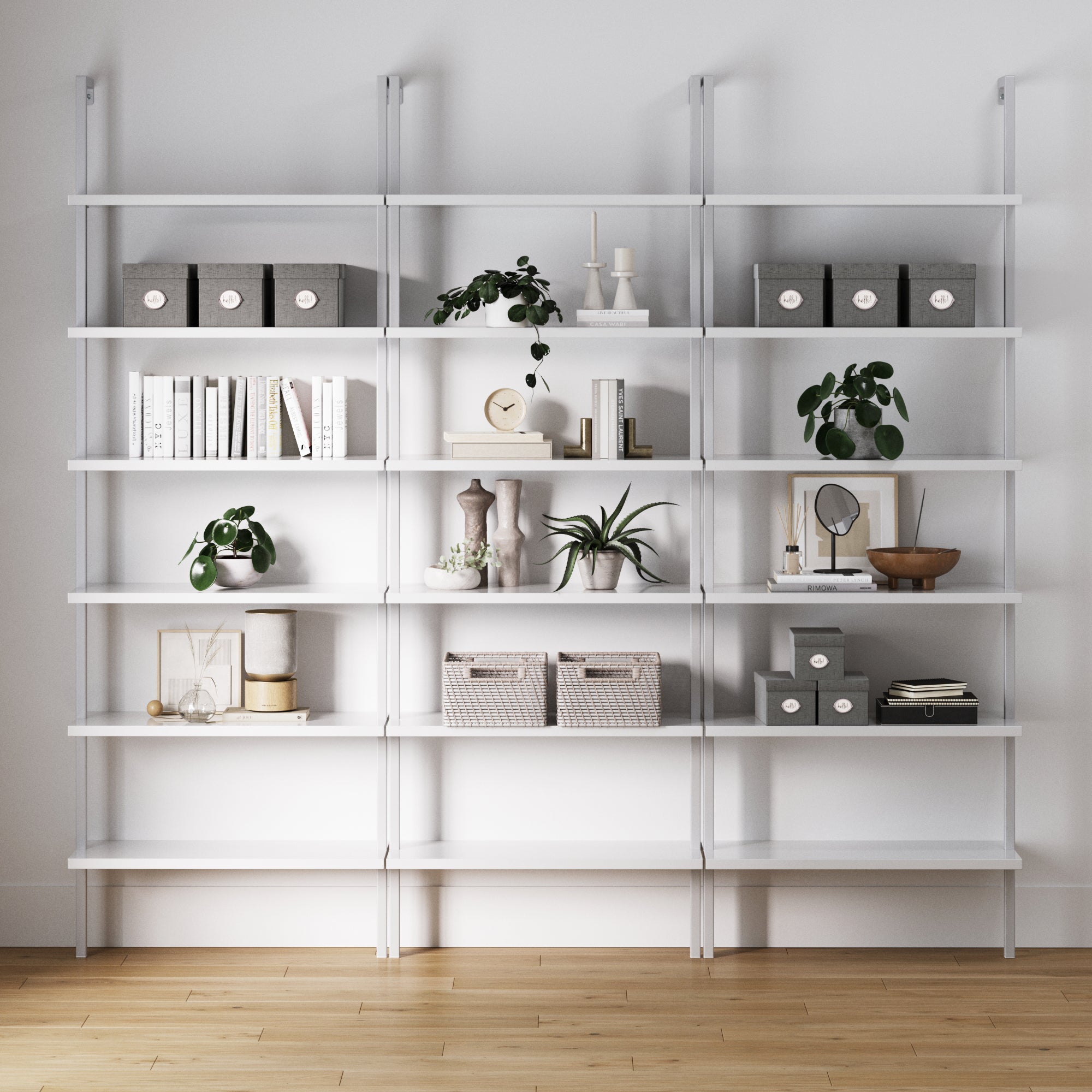 A set of three Nathan James 6-Shelf Ladder Bookshelves in white displays gray storage boxes, woven baskets, books, candles, plants, vases, and decor neatly arranged on their shelves above a light wood floor.