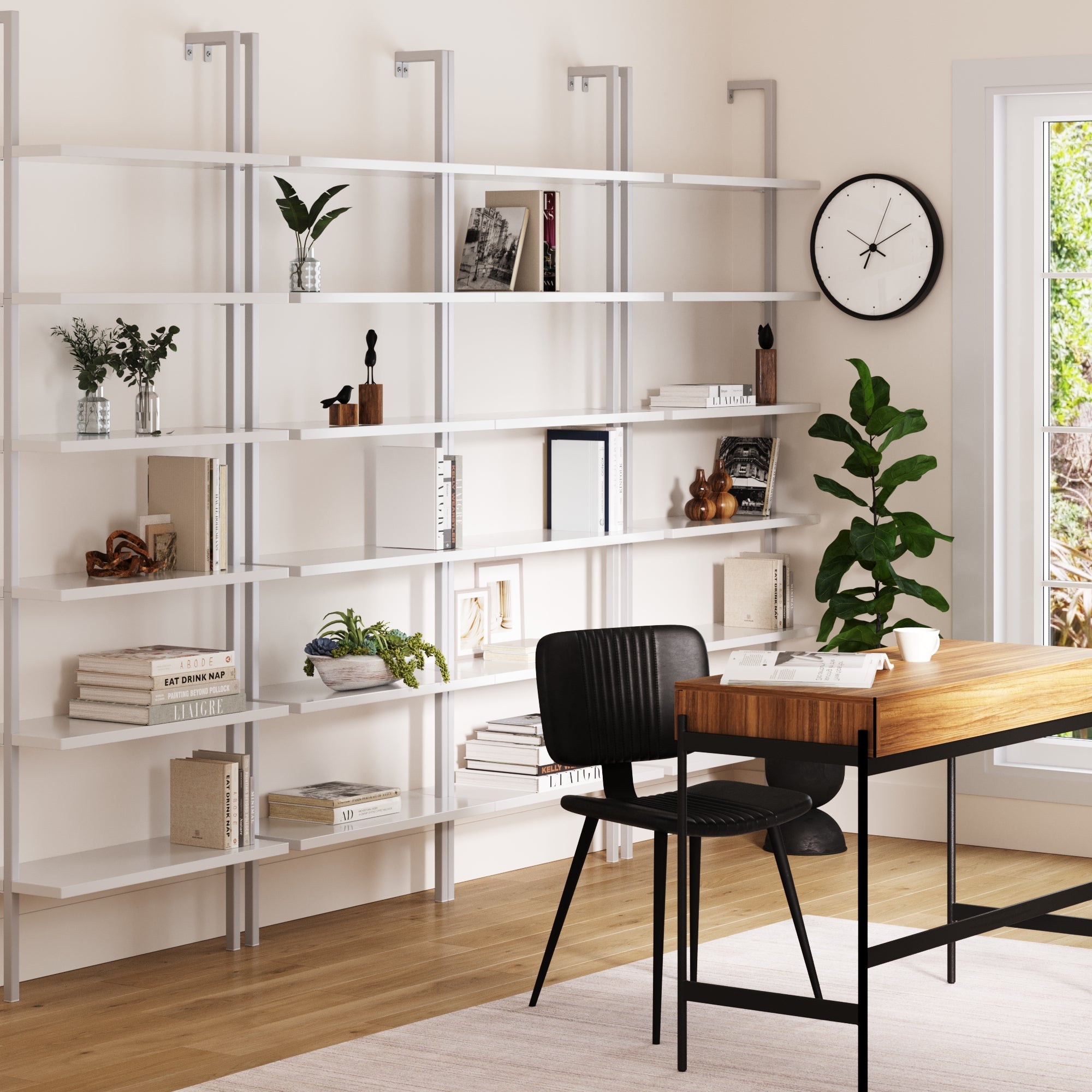 Modern home office features a Nathan James 6-Shelf Ladder Bookshelf White (Set of 4) with books and plants, a wooden desk, black chair, potted plant, wall clock, and large window letting in natural light.
