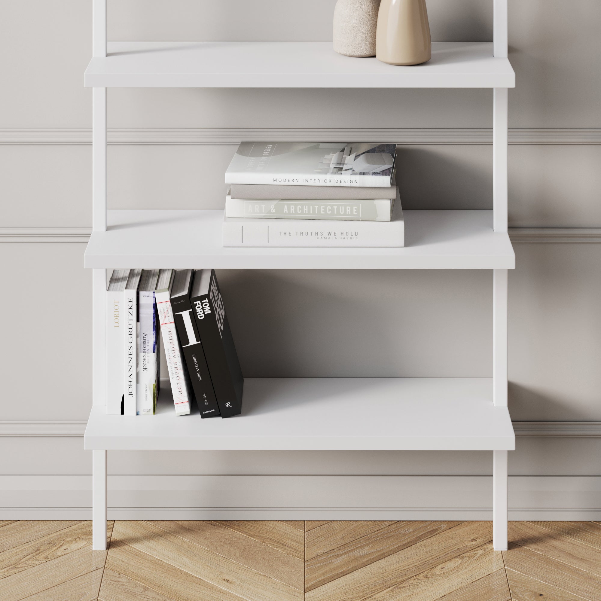 A white bookshelf with stacked books on two shelves; the upper shelf has horizontal stacks, while the lower has vertical books, against a light wall with decorative molding and a wooden herringbone floor. Two beige vases are on the top shelf.