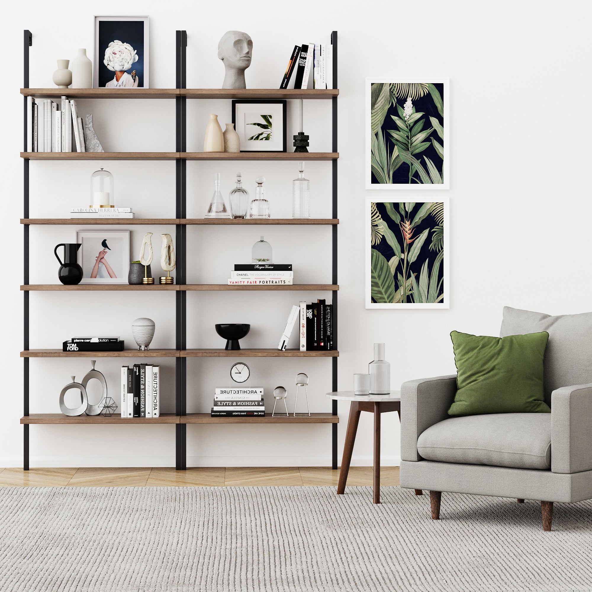 Modern living room with a gray armchair, green and white pillows, a side table, the Nathan James 6-Shelf Ladder Bookshelf in Oak Matte Black styled with books and decor, two framed botanical prints on a white wall, and a neutral rug on wooden floors.