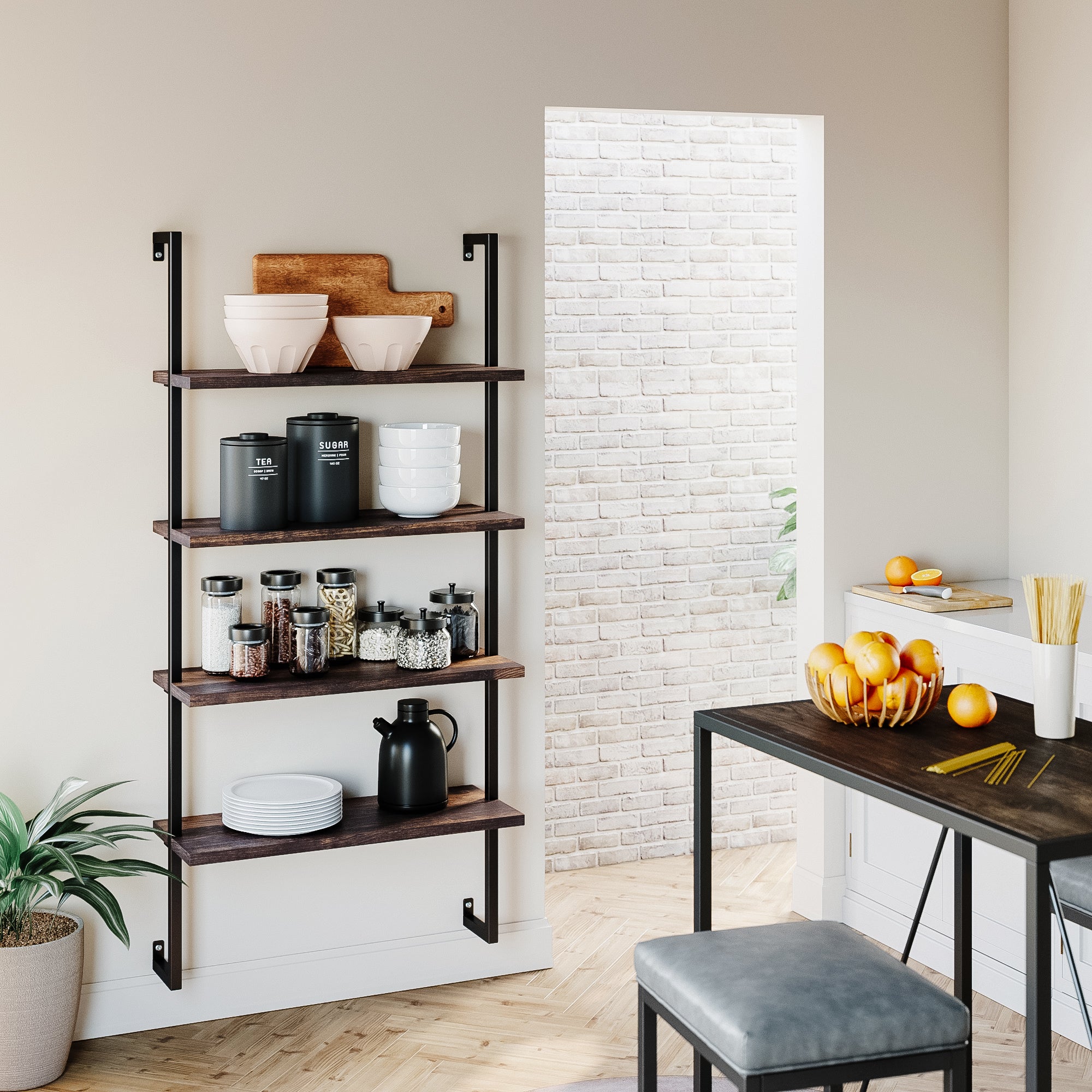A modern kitchen with dark wooden wall shelves holding white bowls, black canisters, jars of food, and a teapot. A plant sits below the shelves. Nearby is a table with oranges, pasta, and a stool. Light streams in from a bright doorway.