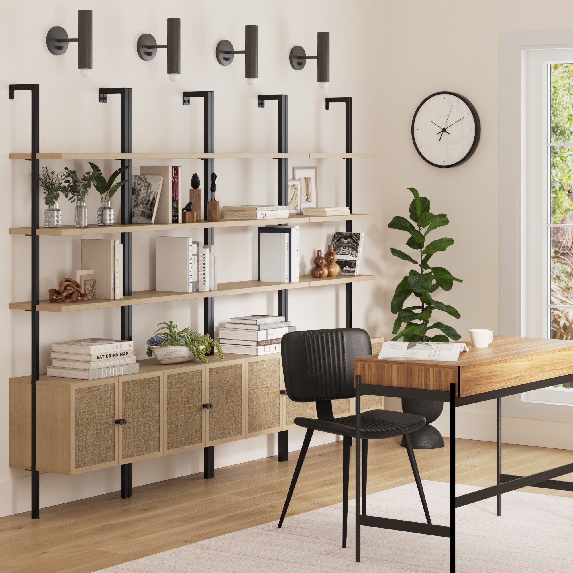A modern home office featuring Nathan James Rattan Ladder Wall Bookshelves with Doors in Light Oak (Set of 4), a wooden desk, black chair, wall-mounted lights, clock, potted plant, and a large window letting in natural light.