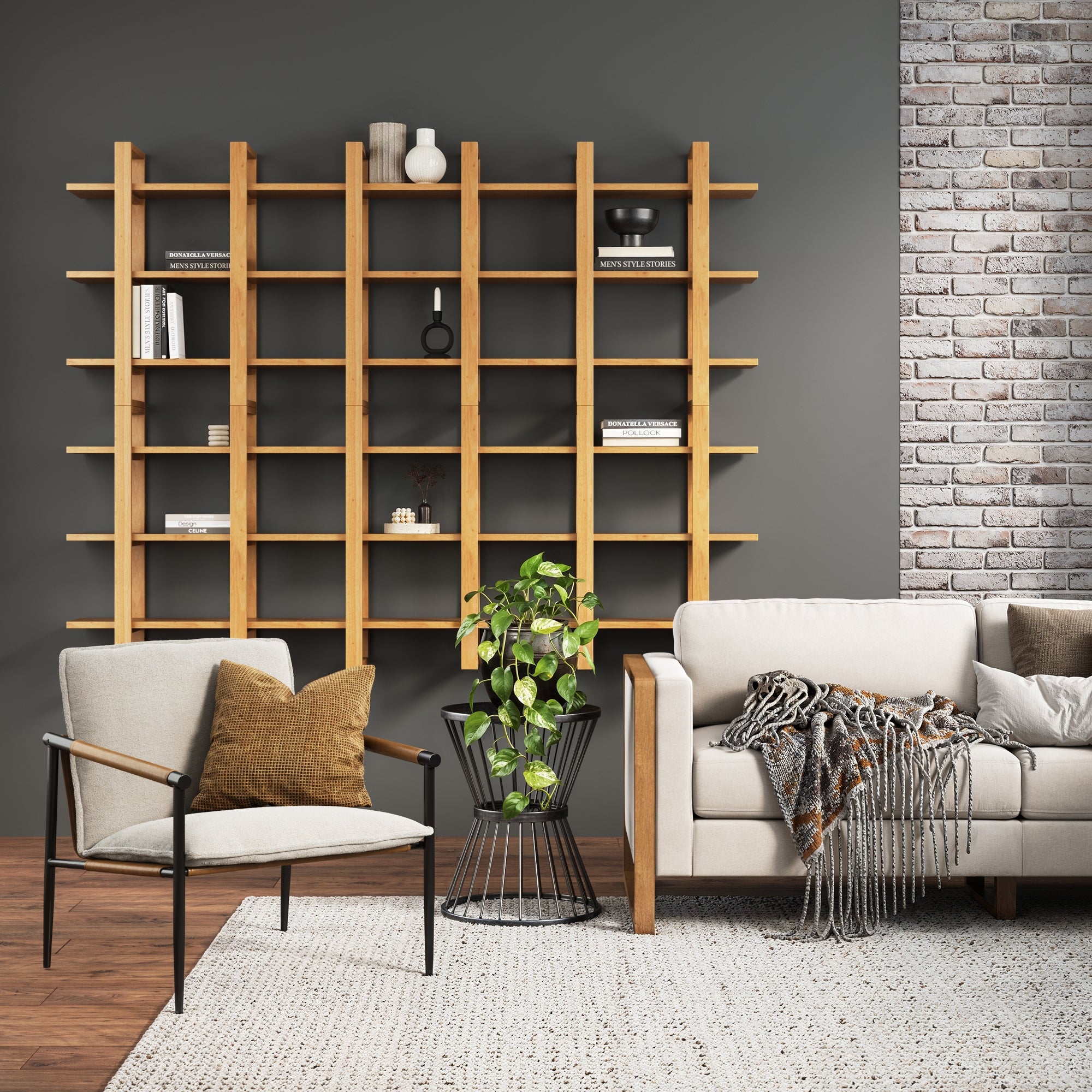 A modern living room features Nathan James Solid Wood Wall Shelves Warm Pine (Set of 6) against a dark wall, minimal decor, a beige armchair with a brown cushion, a cozy sofa with a blanket, a potted plant, and a textured rug.