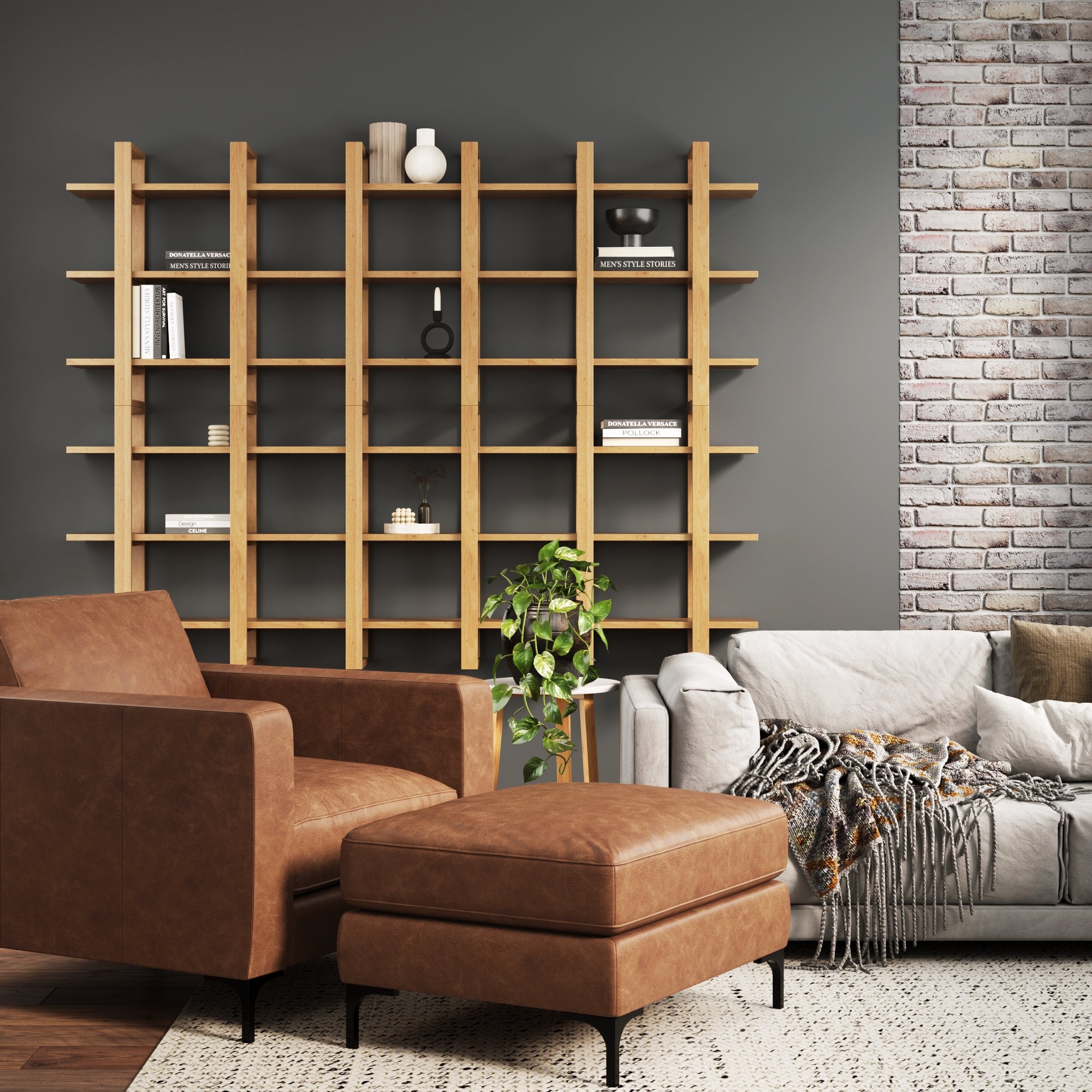 A modern living room with a leather armchair and ottoman, a gray sofa with a throw blanket, a tall wooden bookshelf with minimal decor, a potted plant, and a brick accent wall.