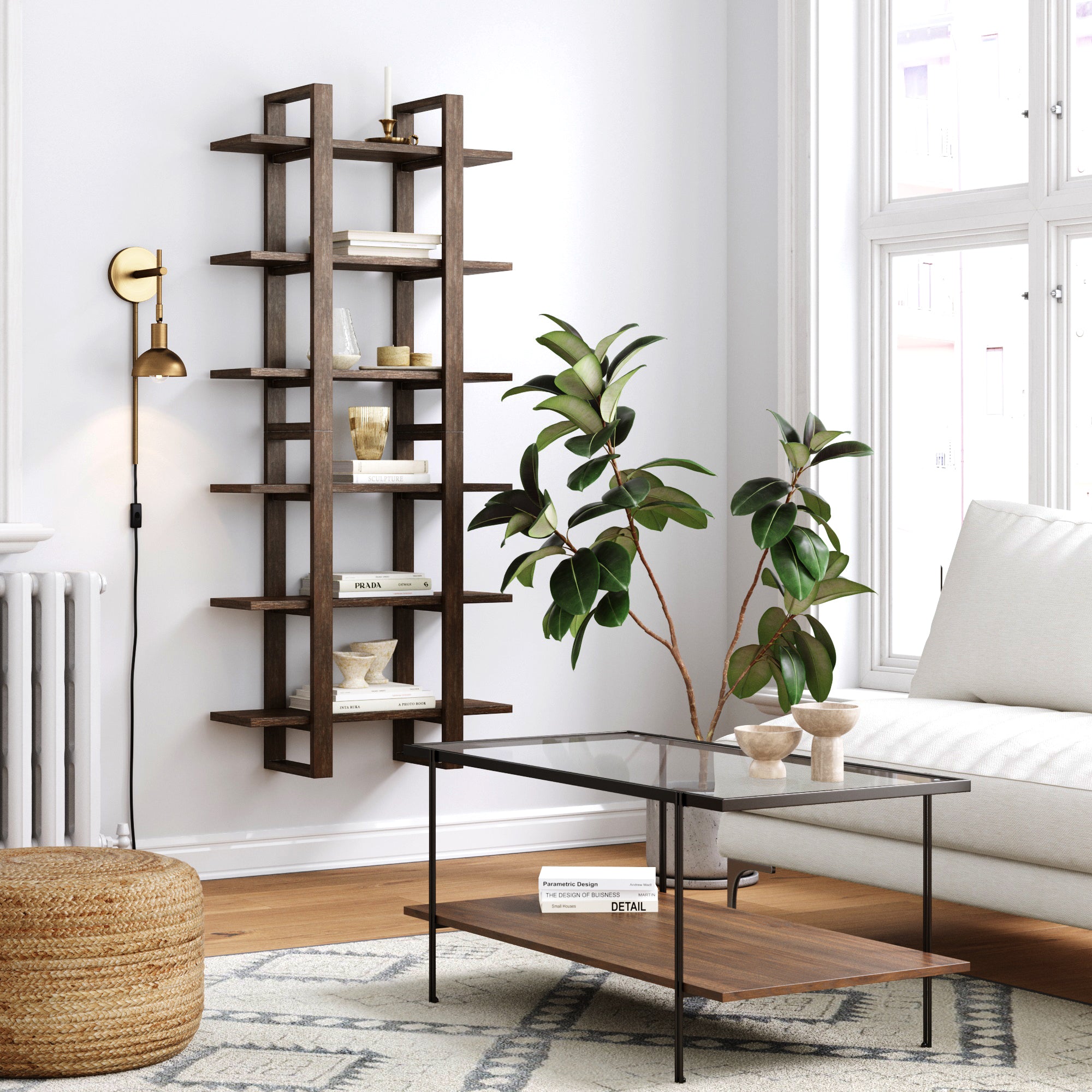 Modern living room with a glass coffee table, a potted plant, a woven pouf, a wall-mounted bookshelf with books and decor, white walls, large windows, and a floor lamp with a gold sconce.