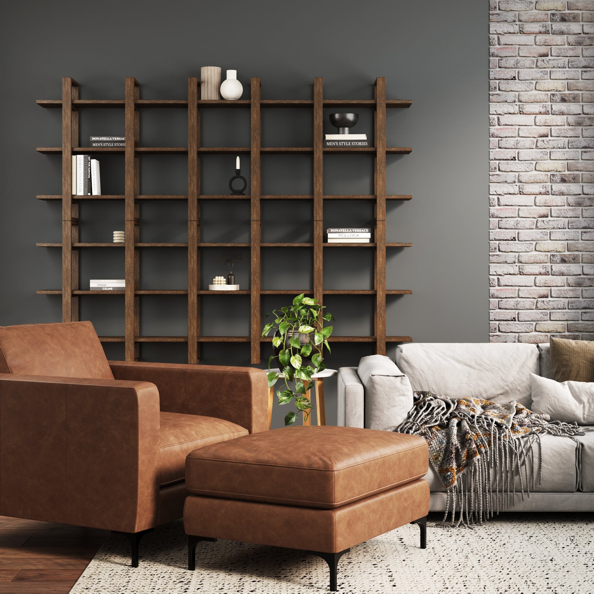 A modern living room with a brown leather armchair and ottoman, a gray sofa with a throw, a wooden shelving unit with decor items, a potted plant, a rug, and a brick accent wall.