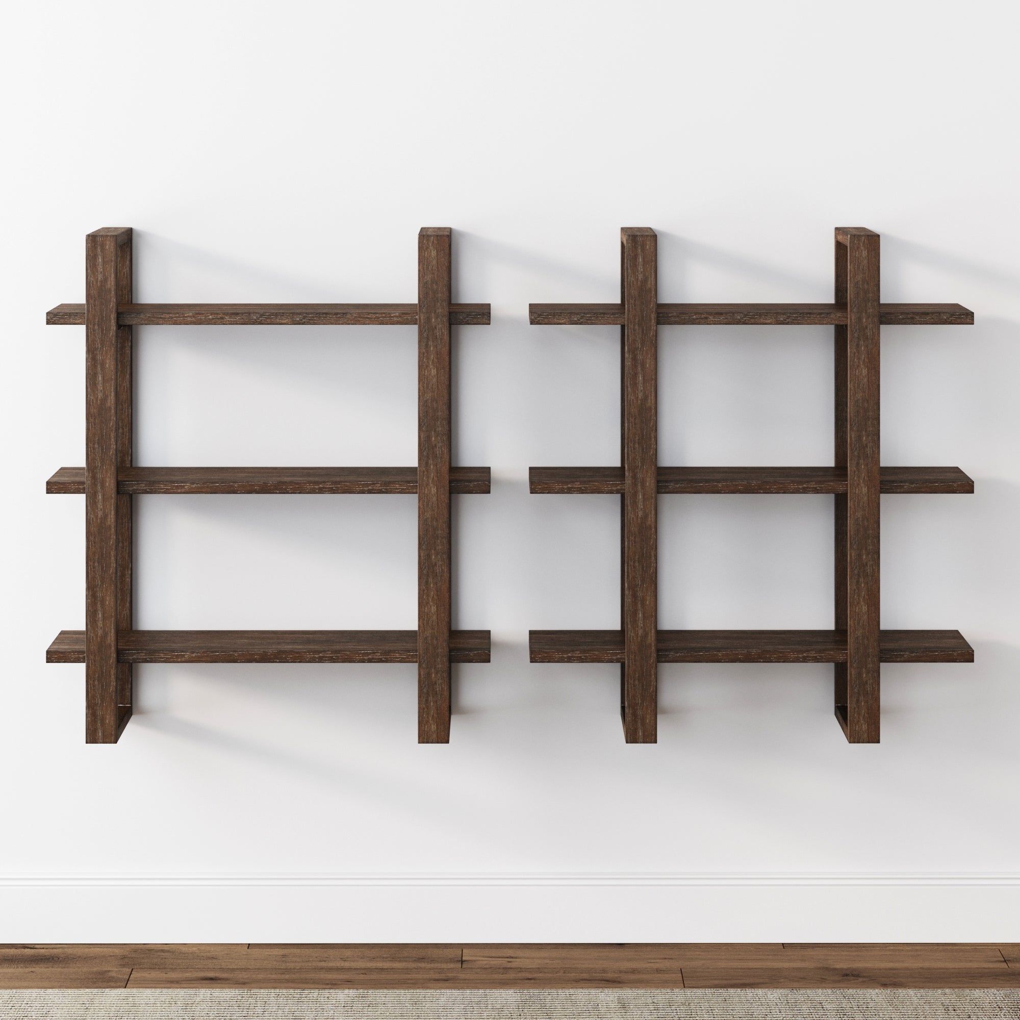 Two modern, dark wood wall-mounted shelves with three tiers each are arranged side by side on a plain white wall above a wooden floor. The shelves have a grid-like, geometric design and are empty.