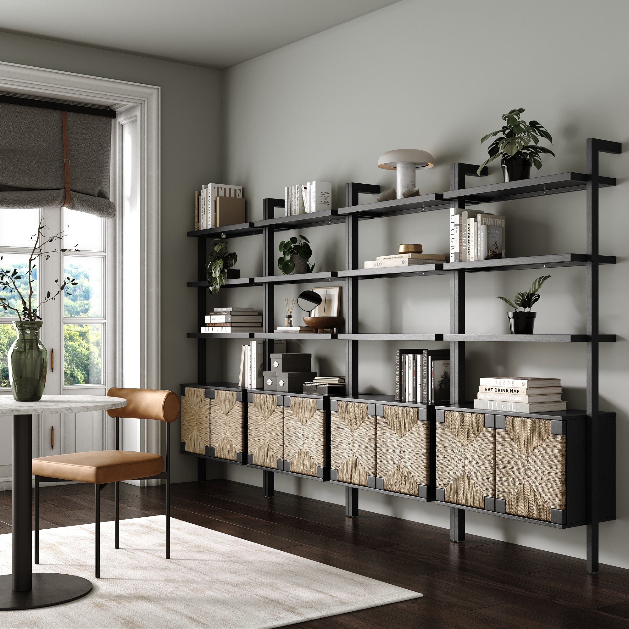A modern home office showcases Nathan James Seagrass Wall Bookshelves with Doors Black (Set of 4), displaying books, plants, and decor. A brown chair pairs with a simple desk near a large window streaming in natural light.