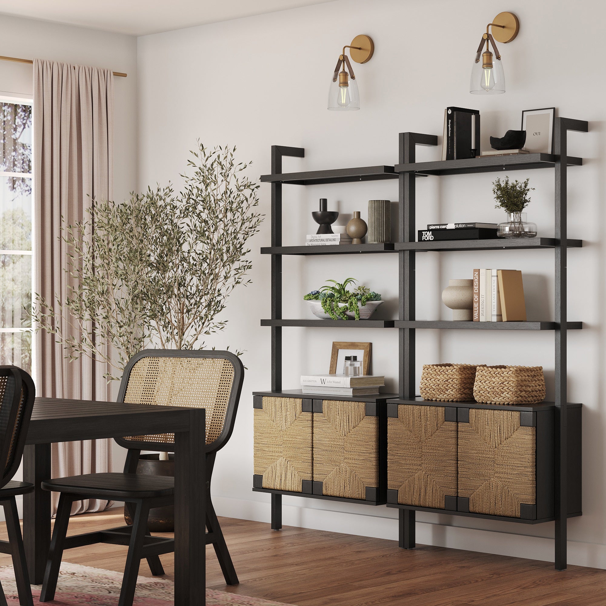 A modern dining room features a black solid wood dining set with woven seats, complemented by the Nathan James Seagrass Wall Bookshelf with Doors in Black styled with books, plants, and decor. Tall curtains and a potted tree add coziness.