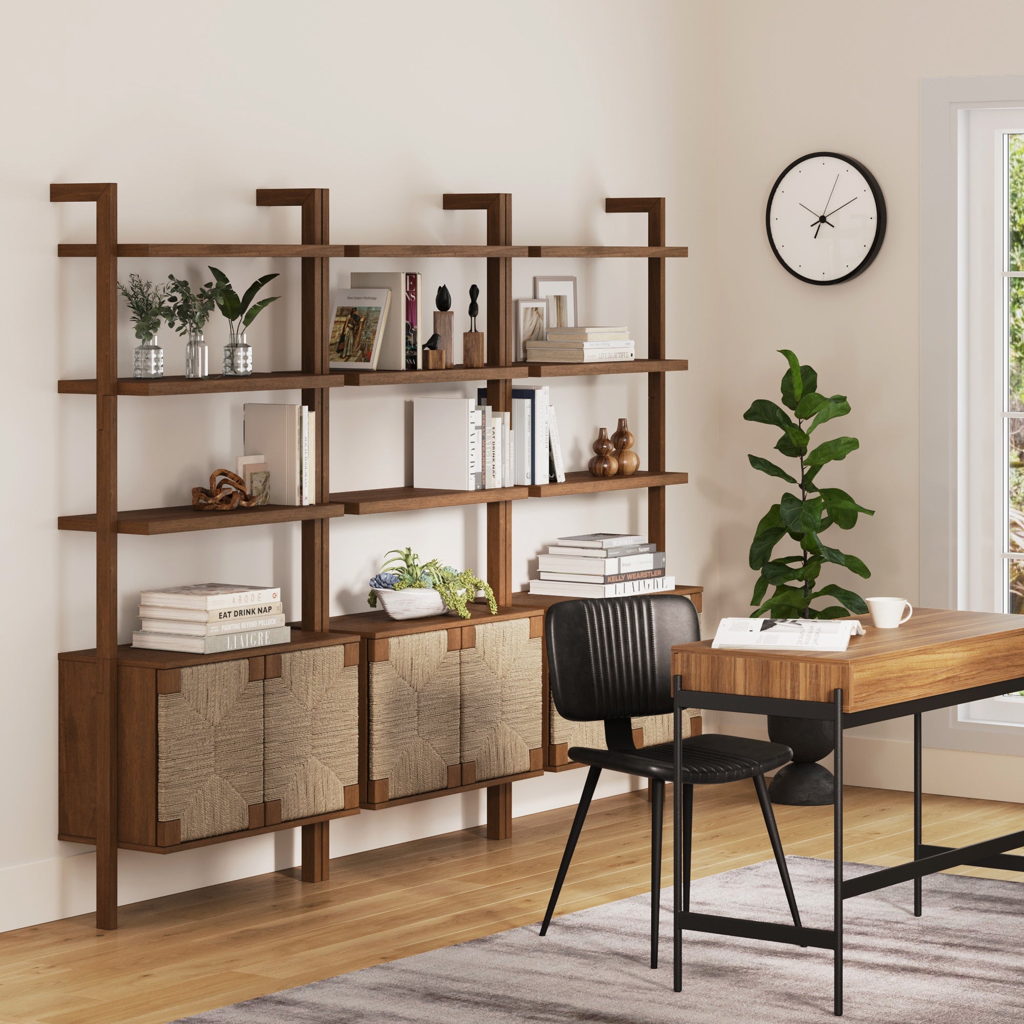 A modern home office features a solid wood desk, black chair, large Nathan James Seagrass Wall Bookshelves with Doors Dark Brown (Set of 3), wall clock, potted plant by the window, and a light rug on wooden floors.