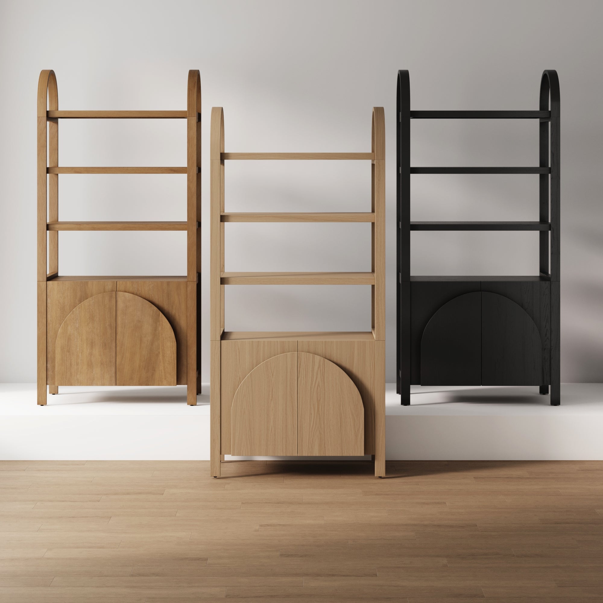 Three wooden shelving units stand side by side on a white platform, each with an arched design and cabinet doors at the bottom. The units are in light wood, medium wood, and black finishes.