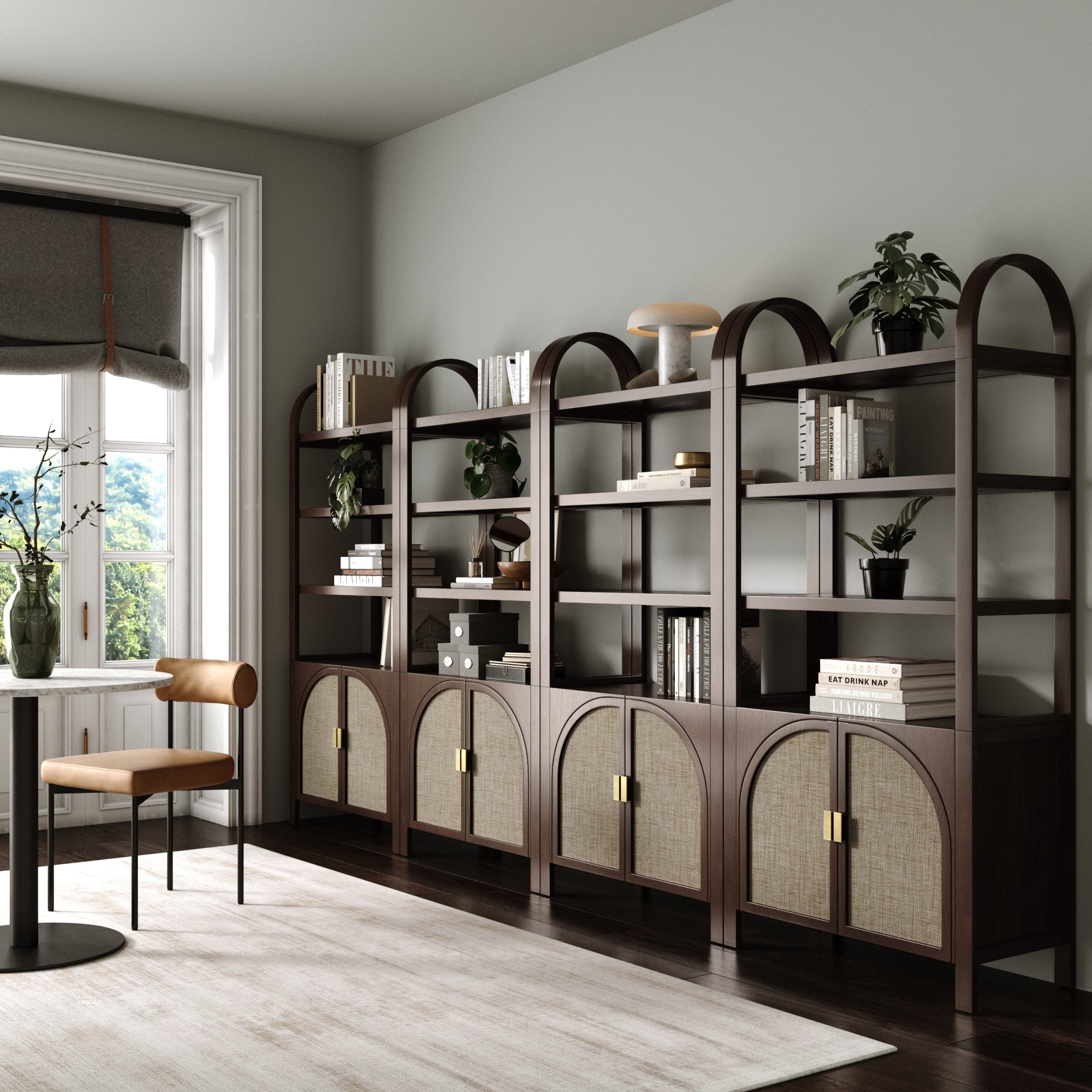 A modern home office features a large window, a brown desk and chair, and four Nathan James Arched Door Rattan Bookshelves in Dark Acacia, with solid wood frames and woven arched doors displaying books, plants, and decor above cabinets.