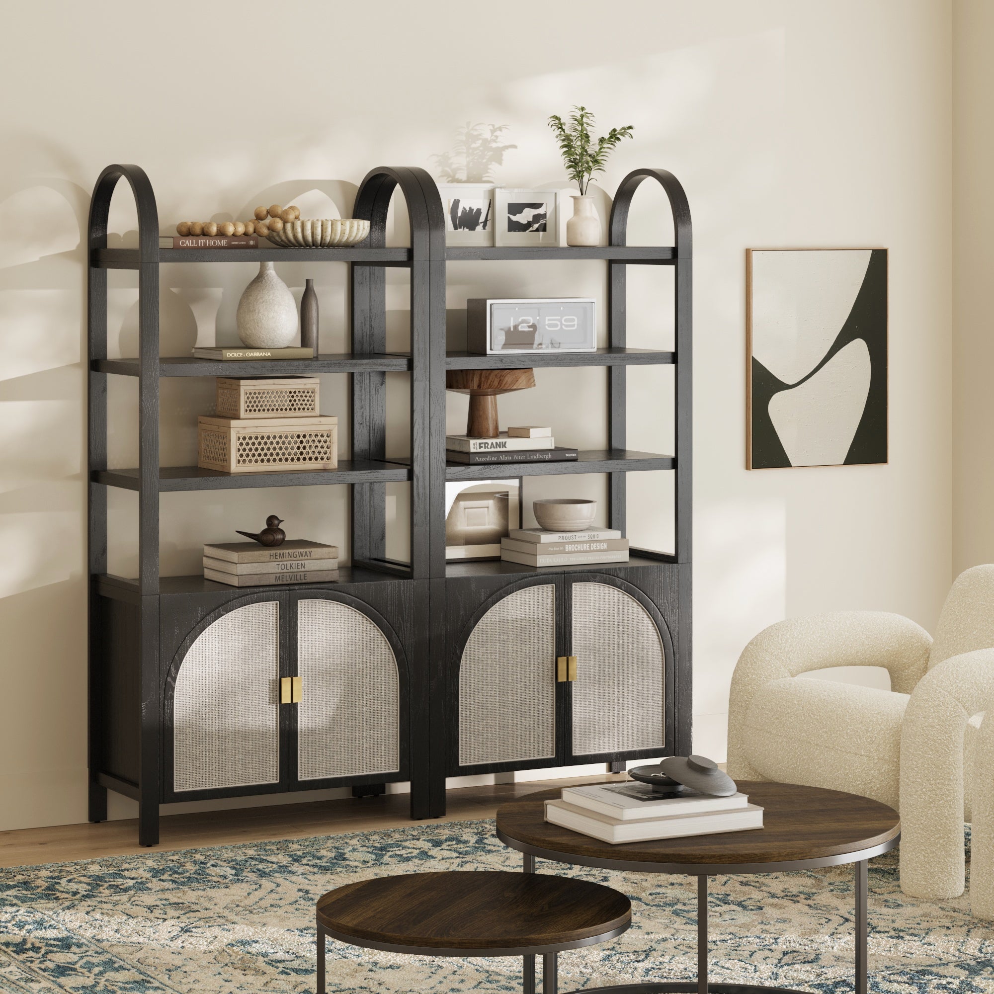 Two Nathan James Arched Door Rattan Bookshelves in Black Oak (set of 2) with cabinets display books, vases, baskets, and sculptures beside a round coffee table, curved cream chairs, and abstract wall art in a sunlit living room.