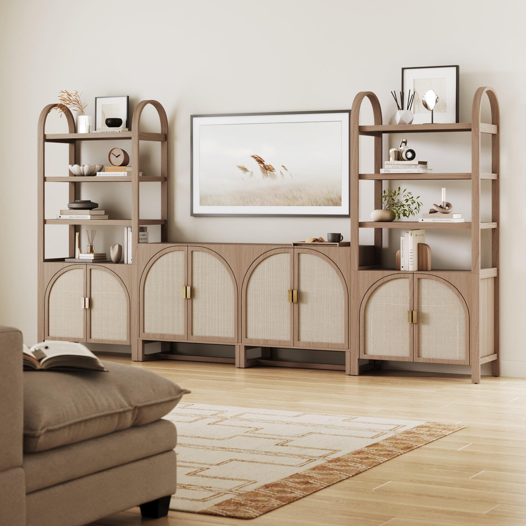 A modern living room with a beige sofa, a patterned rug, and a large wooden shelving unit with arched shelves, decorative items, books, and a framed artwork of grasses on the wall above the unit.