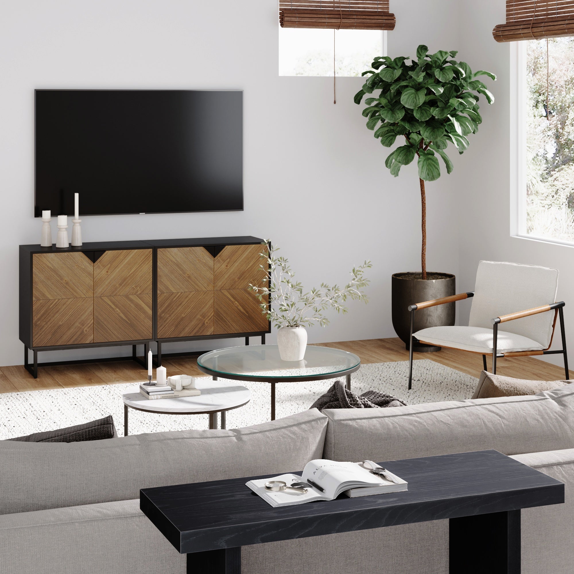 Modern living room with a wall-mounted TV, wooden cabinet, round glass coffee table, potted plant, armchair, and neutral decor. Light streams in through windows with bamboo blinds.