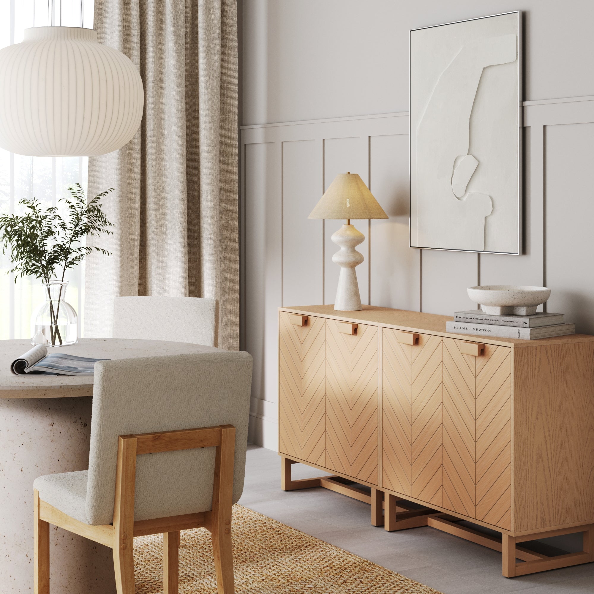 A modern dining room features a round table, beige upholstered chairs, two Nathan James Wood Herringbone 2-Door Accent Cabinets in Raw Oak as sideboards, contemporary art, a table lamp, neutral decor, and a large window with sheer curtains.