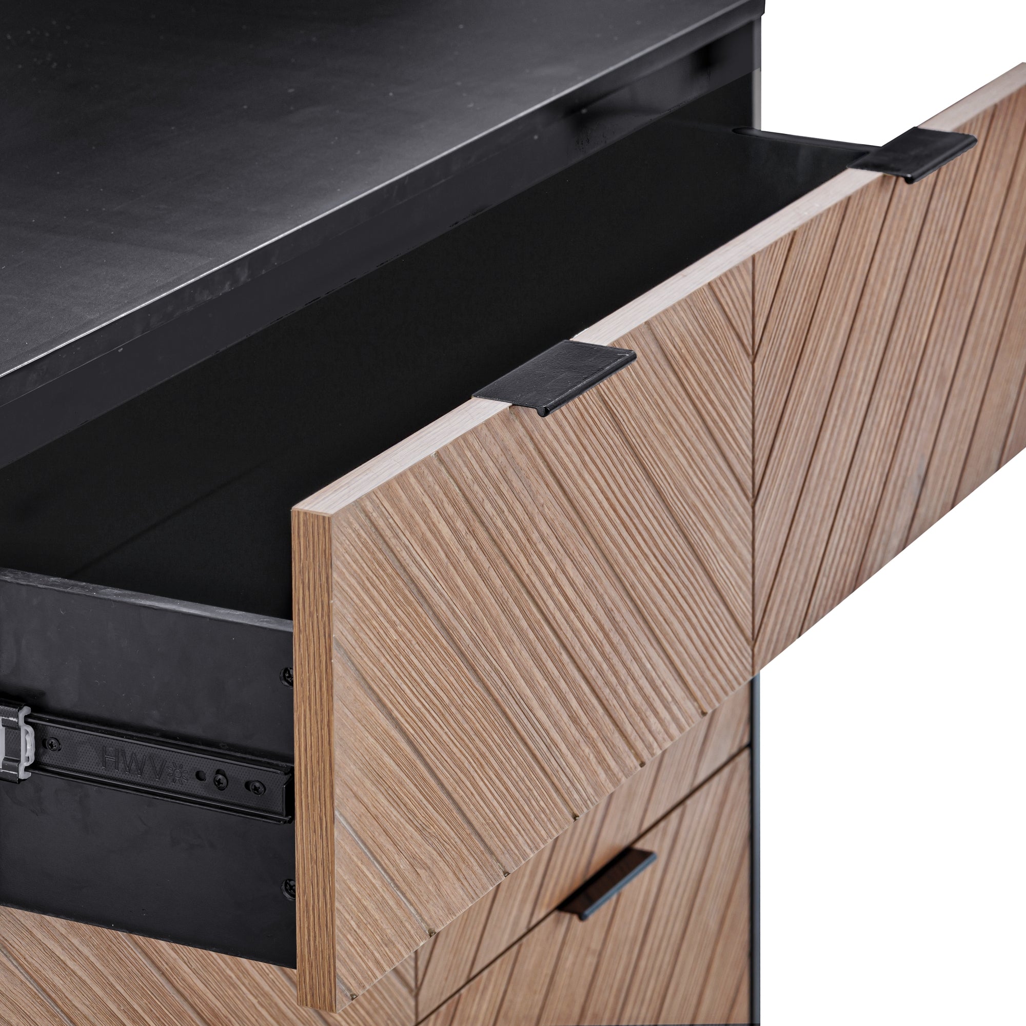 A close-up of a wooden cabinet with a chevron pattern, showing the top drawer partially open. The cabinet has modern black handles and a matte black countertop.