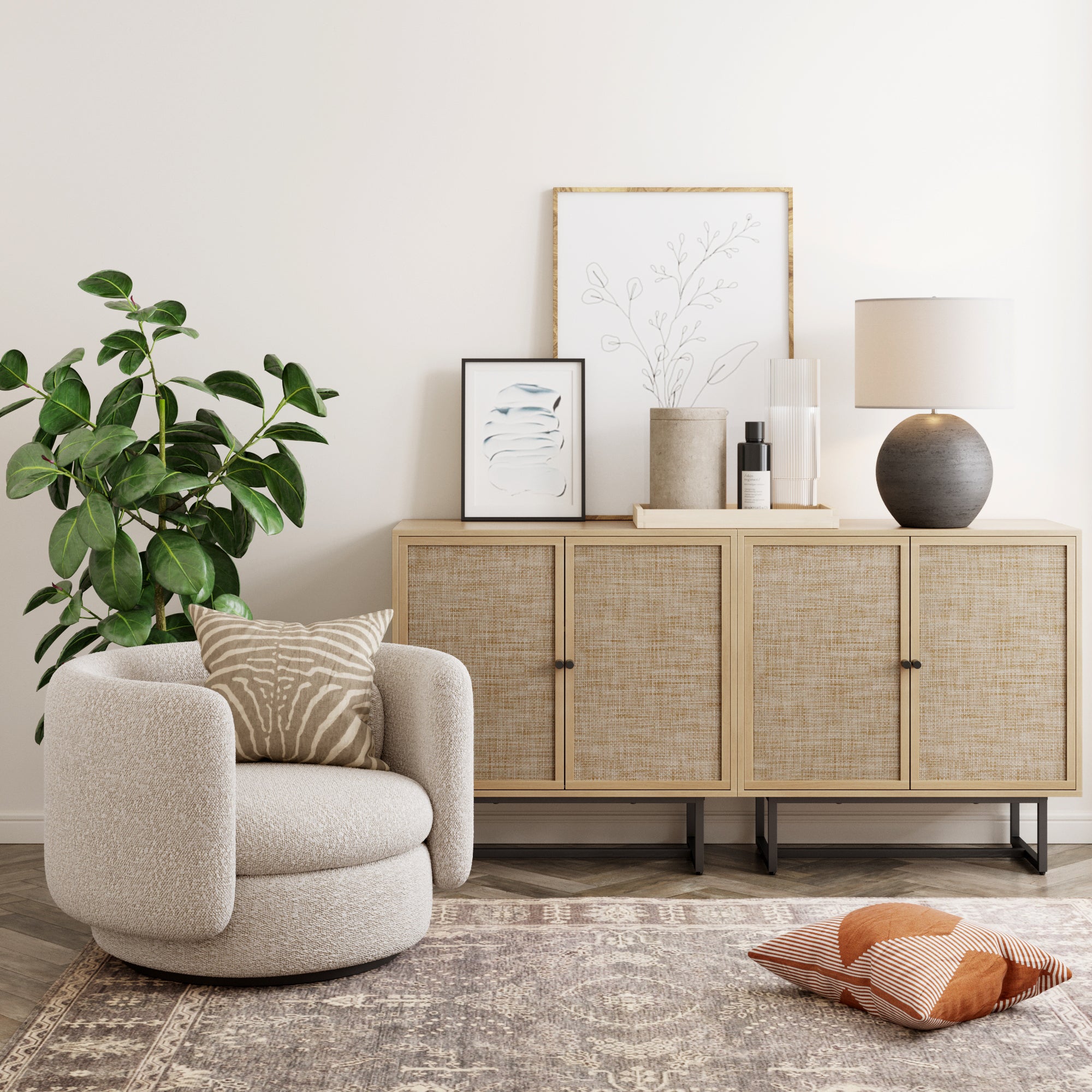 A cozy modern living room corner with a rounded beige armchair, a patterned cushion, a sideboard with framed art and a lamp, a potted plant, a patterned rug, and two floor cushions.