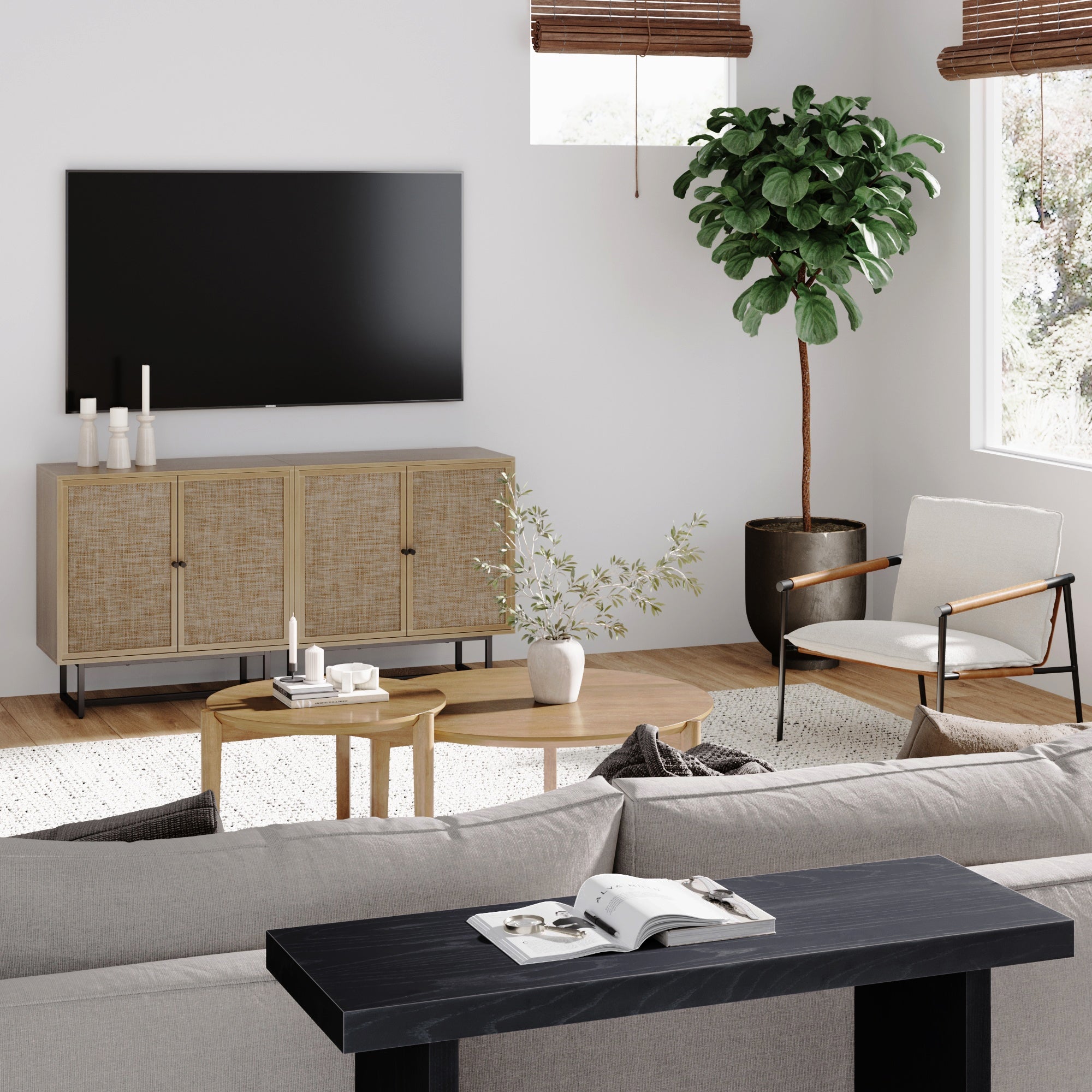 Modern living room with a wall-mounted TV, light wood cabinet, potted tree, white armchair, round wood coffee table, and beige sofa. Room features minimal decor with natural light through window blinds.