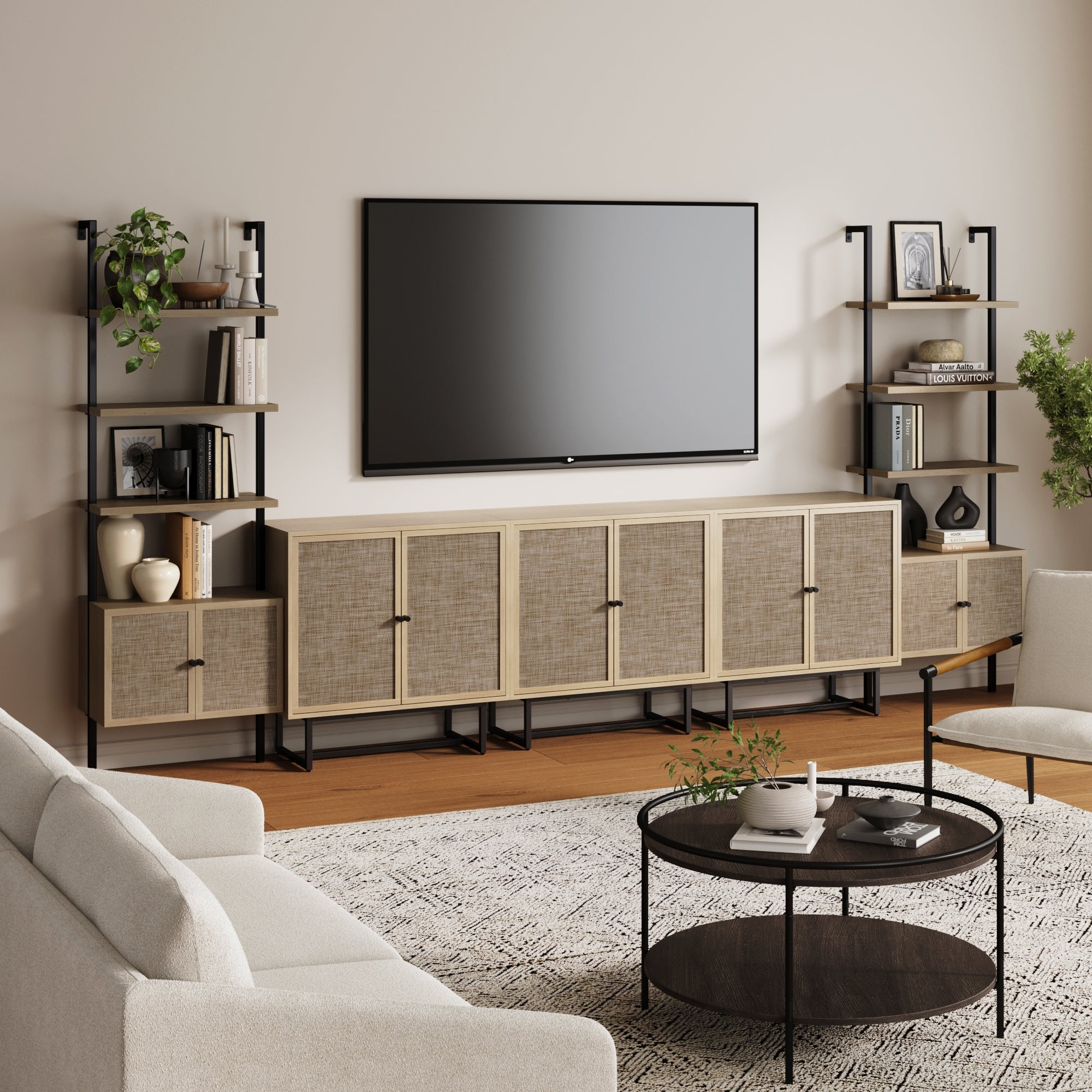 A modern living room showcases the Nathan James Boho Rattan Entertainment Center (3 Cabinets) beneath a wall-mounted TV, with oak bookshelves on either side; a round coffee table, light sofa, and patterned rug complete the cozy décor.