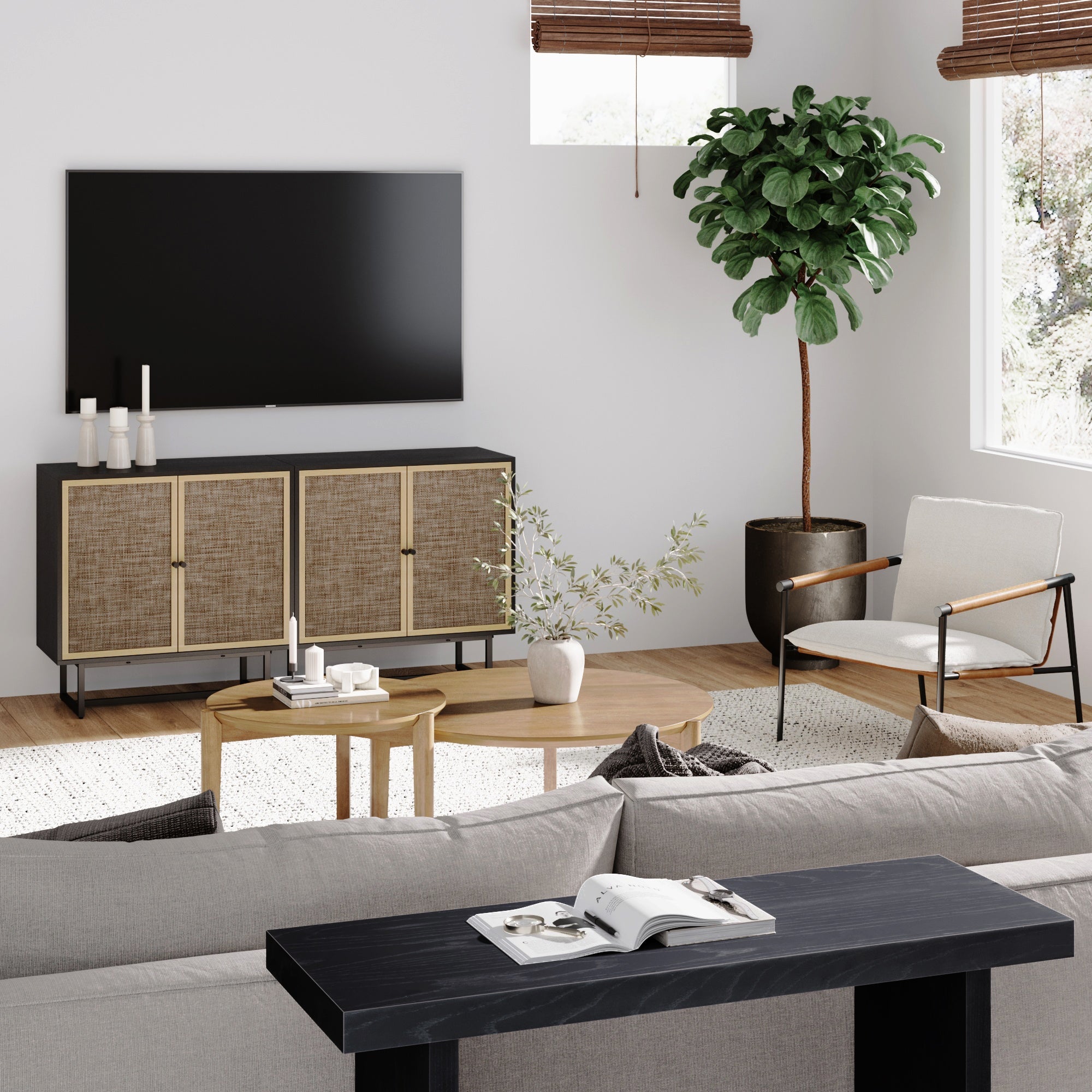 A modern living room with a wall-mounted TV, a light beige sofa, a wooden coffee table, a side cabinet with cane doors, a white armchair, a large potted plant, and natural light from windows with bamboo shades.