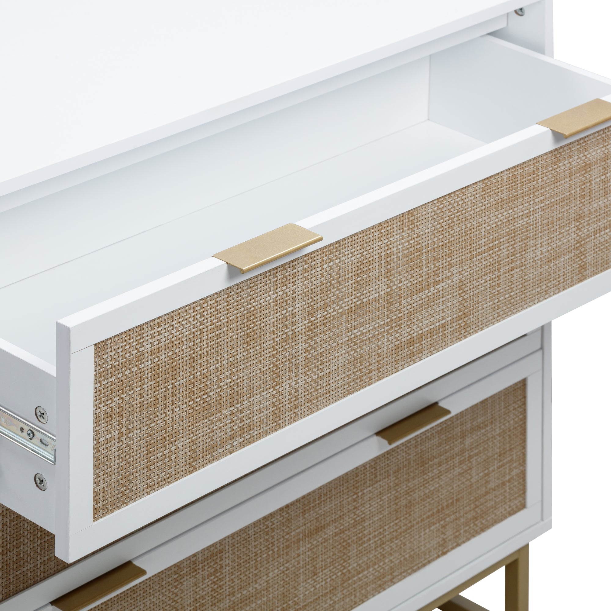 A close-up of a white dresser with a textured, light brown woven front. One drawer is partially open, showing its empty interior. The drawer has a rectangular gold handle.