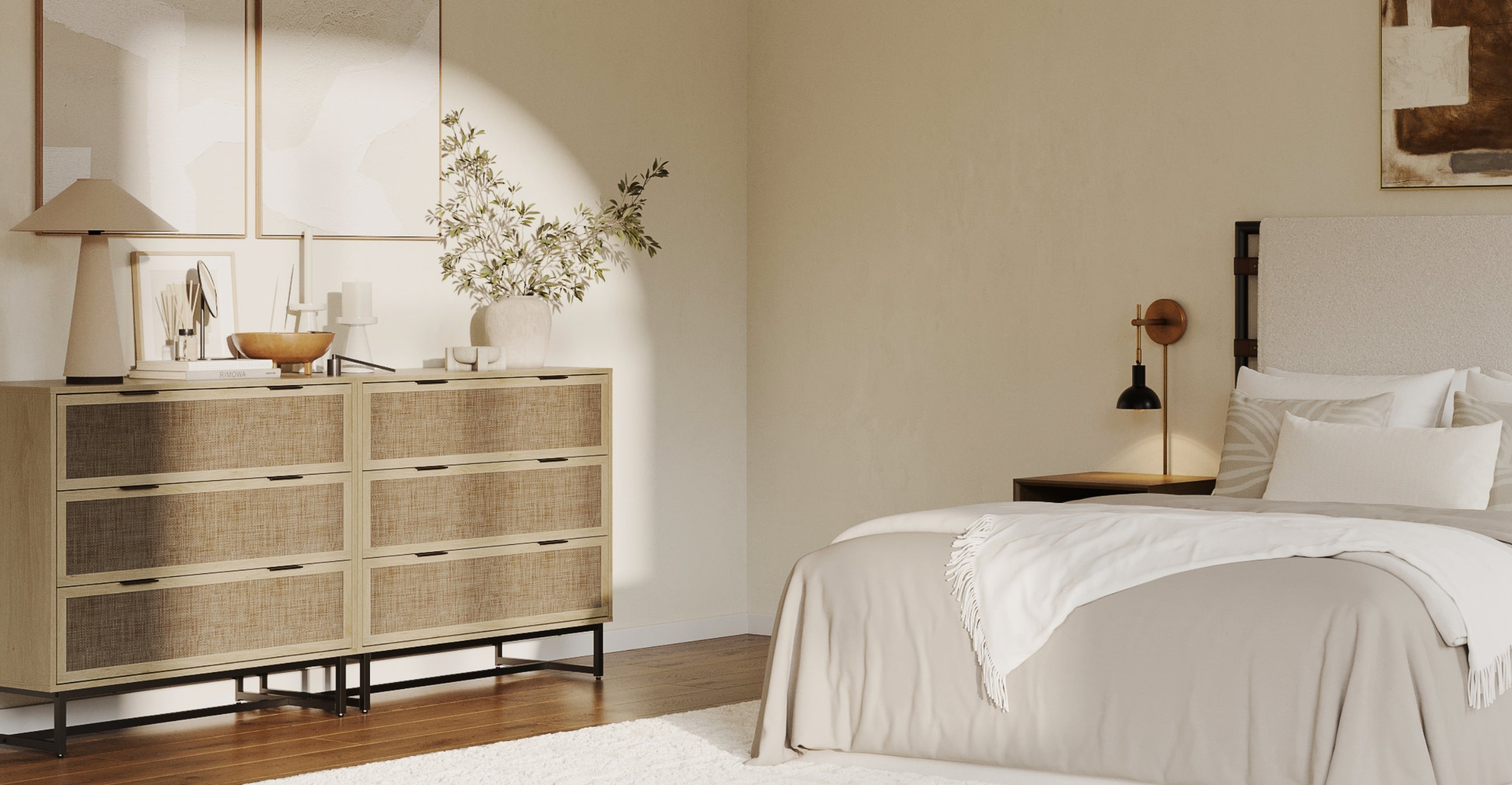 A modern, sunlit bedroom features a beige bed with white pillows and a light blanket, a nightstand with a wall lamp, and a dresser adorned with decorative items and a vase of greenery, all in neutral tones.