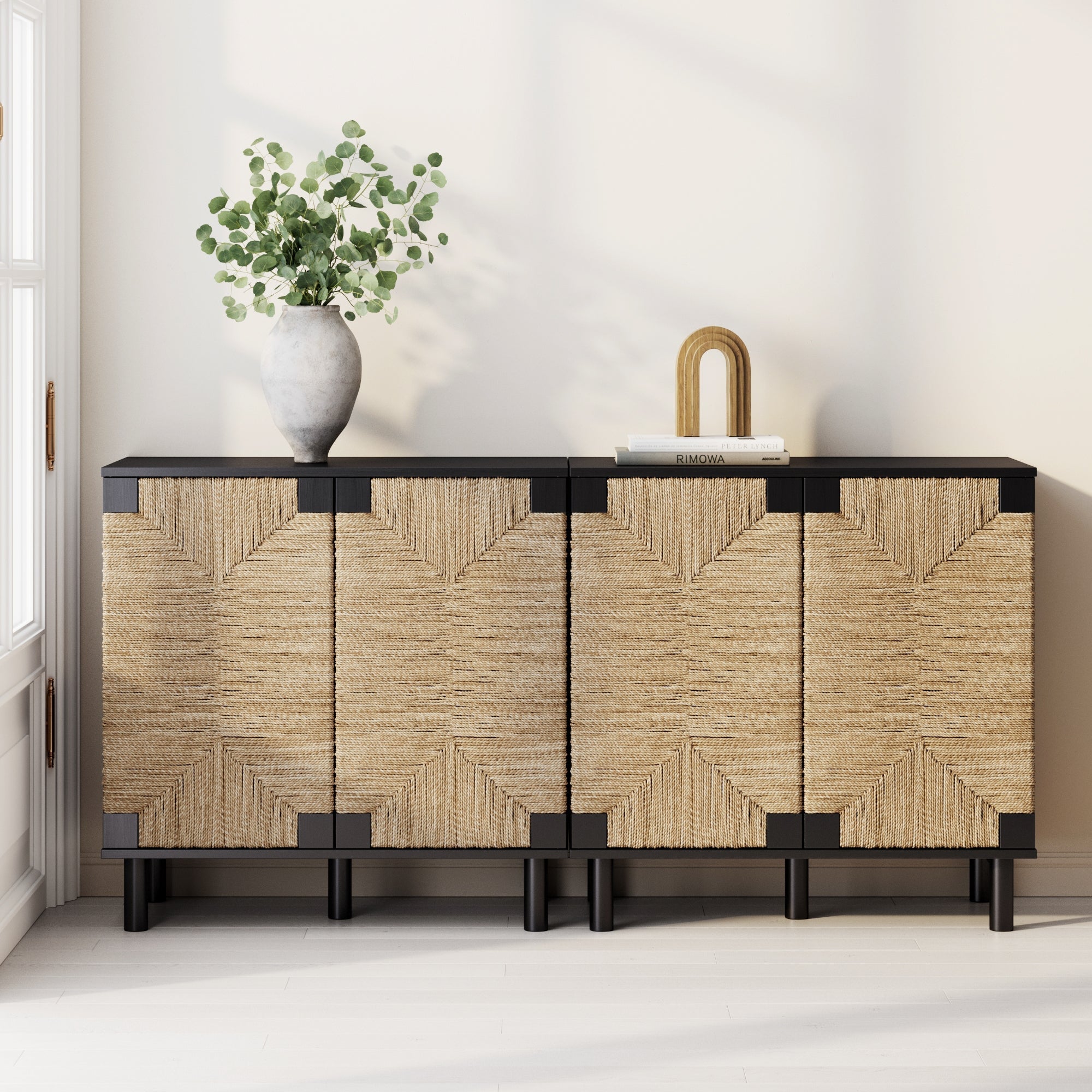 The Nathan James Seagrass TV Console Credenza in black (set of 2) features woven rattan doors and a sleek frame, adding subtle bohemian flair to any room when styled with decorative accents against a light wall.