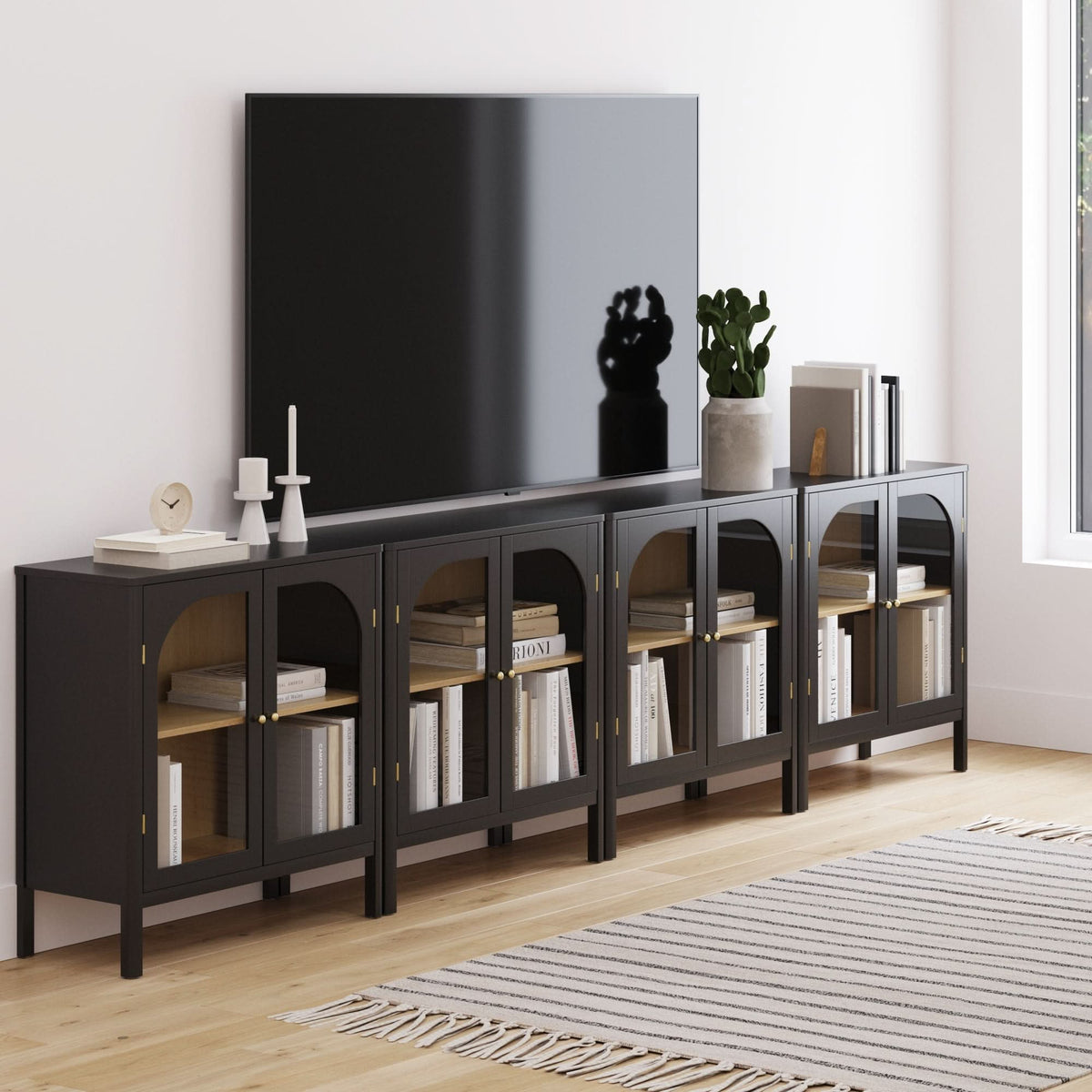 Four Nathan James Large Glass Door Curio Cabinet Credenza Black units with arched glass doors and brass hardware arranged as a transitional media console under a wall-mounted television.