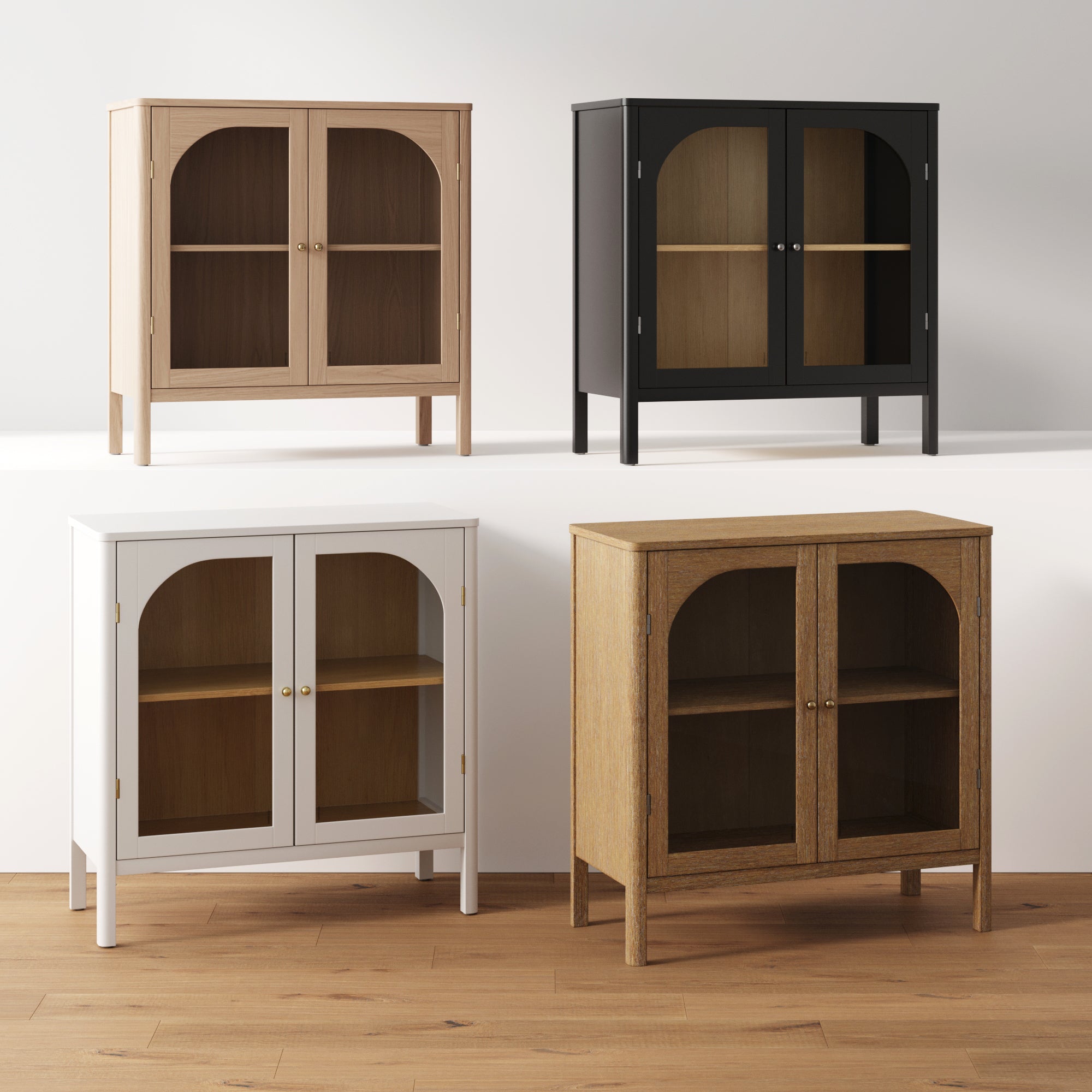 Four glass-door cabinets in different finishes—light wood, black, white, and medium wood—are arranged on a white platform and wooden floor against a plain background. Each cabinet has two doors and a shelf inside.