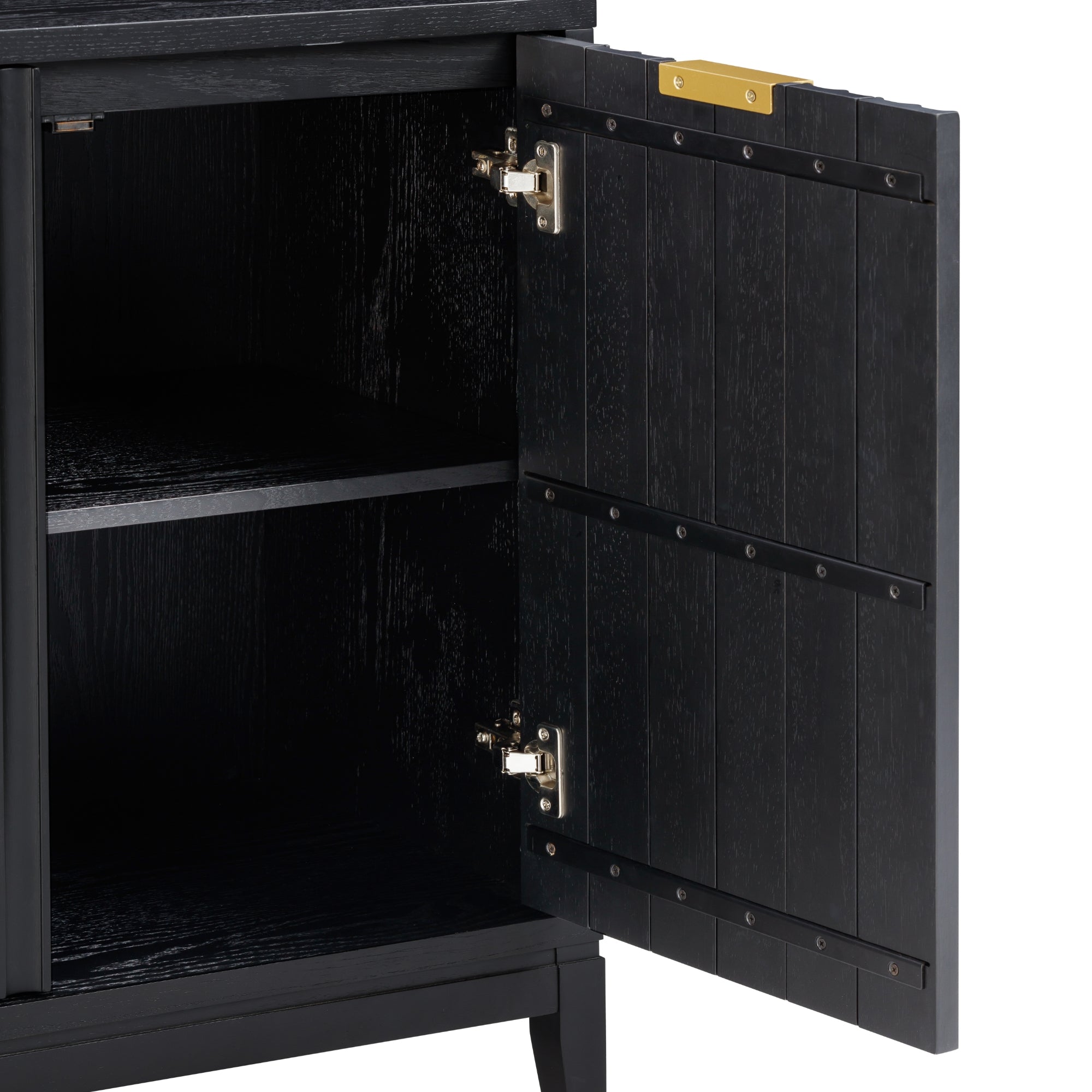 A close-up of an open black wooden cabinet door with metal hinges, revealing an empty interior shelf. The door has vertical grooves and a brass-colored plate at the top edge.