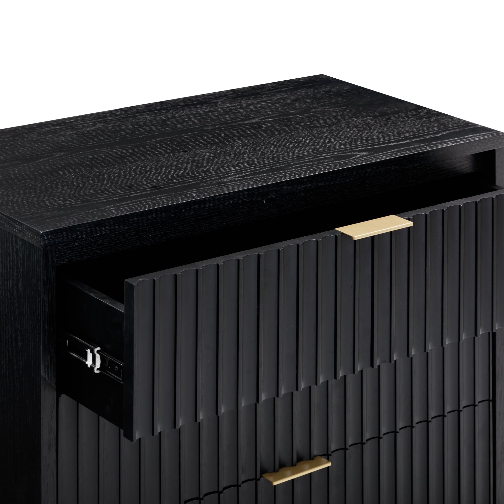 A close-up of a black wooden cabinet with vertical grooves, gold handles, and an open top drawer. The design is modern and sleek.
