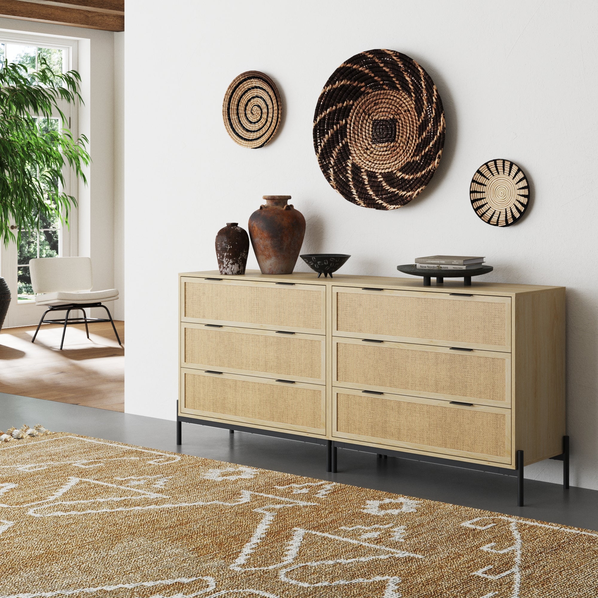 A modern room showcases Nathan James Rattan & Wood Dressers Light Oak (Set of 2), featuring black handles and a safety interlock. Three vases, ceramic plates, woven baskets above, and a tan patterned rug complete the look.