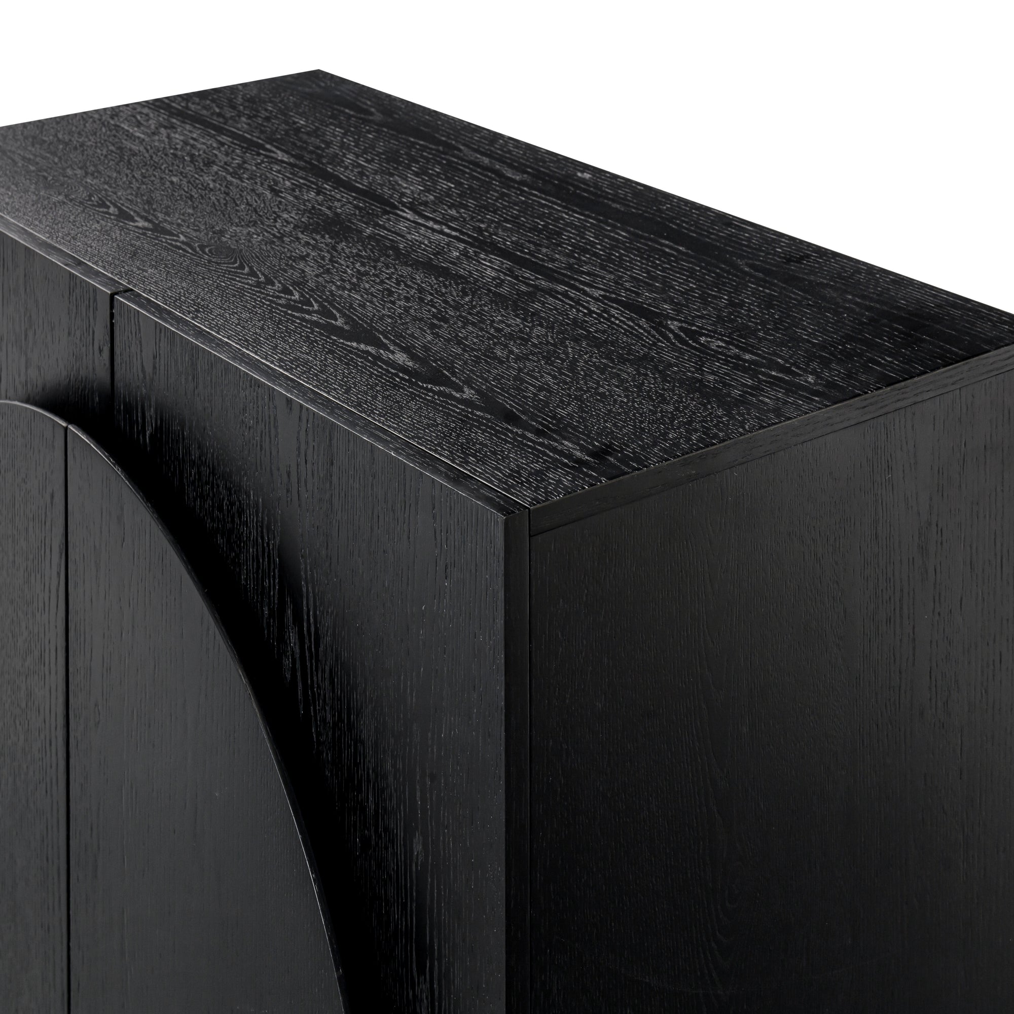 A close-up of a modern black wooden cabinet with a textured, wood grain finish and a smooth, geometric design. The photo highlights the top and side surfaces.