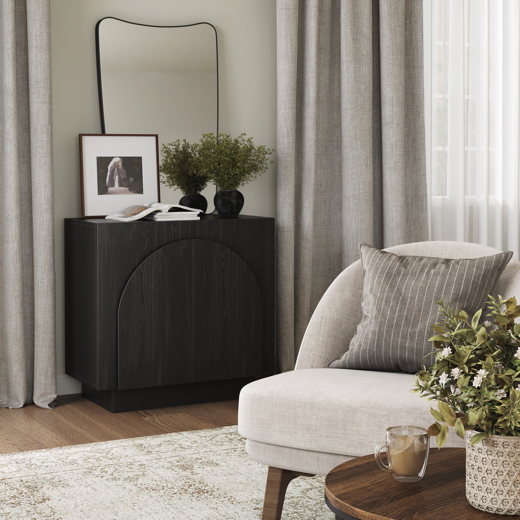 A cozy living room corner with a light armchair, round wooden table with a potted plant, a dark cabinet with a framed photo, vase, and a wavy-edged mirror, all set against light curtains and a window.