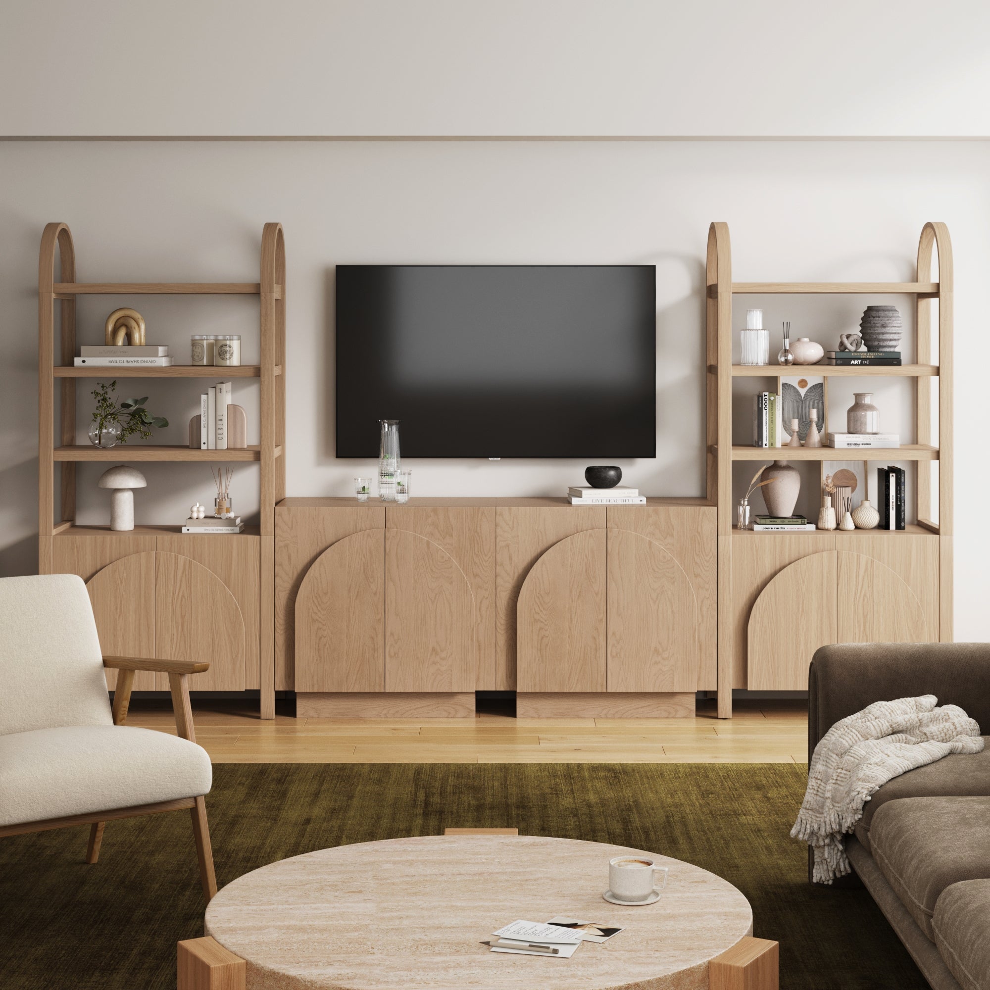 A modern living room with neutral tones features a large TV on a wooden media console with arched cabinets and open shelves. The room includes a beige armchair, brown sofa, round coffee table, and decorative objects.