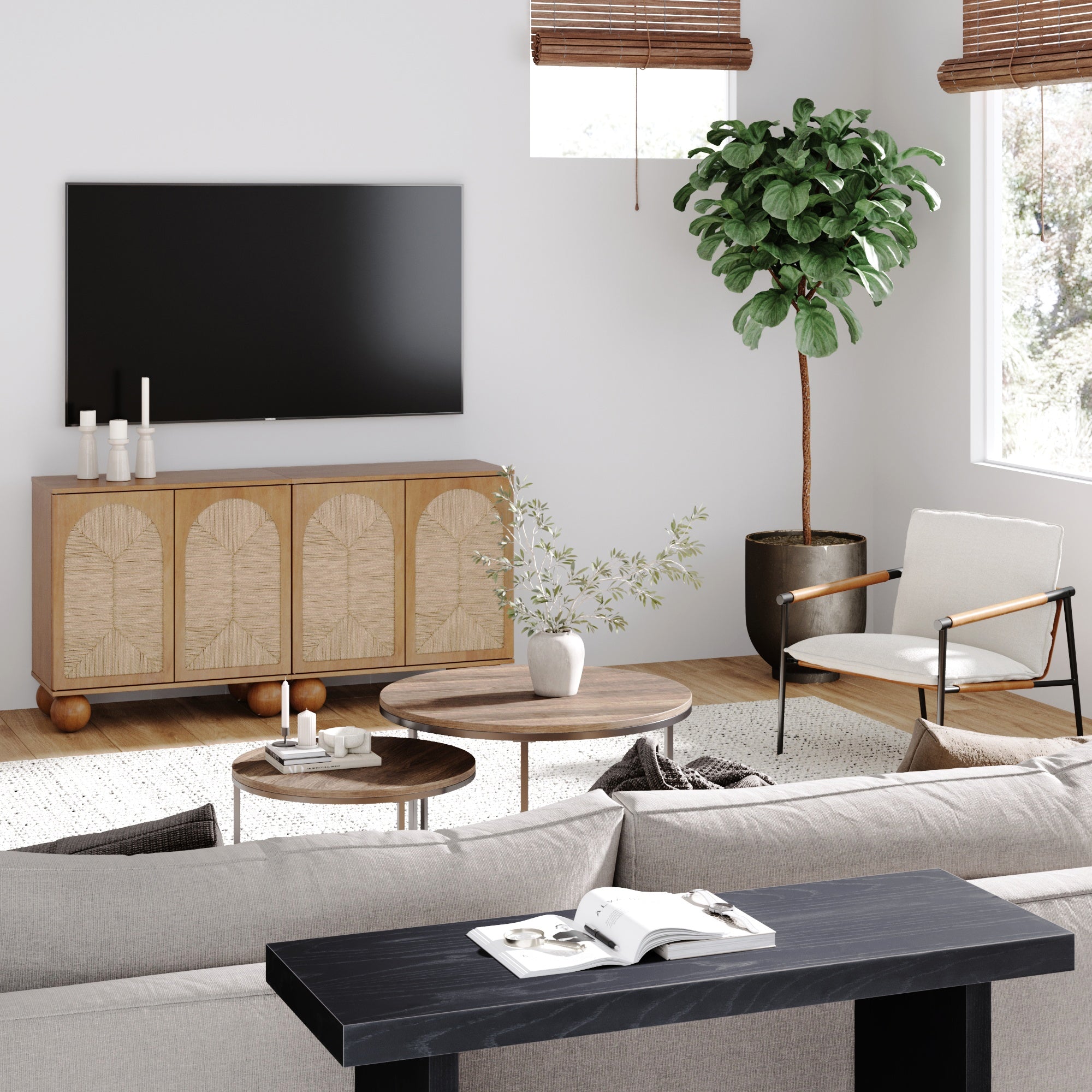 A modern living room with a wall-mounted TV, wooden sideboard, round coffee tables, a potted plant, an armchair, and a beige sofa. Natural light streams in through windows with wooden blinds.