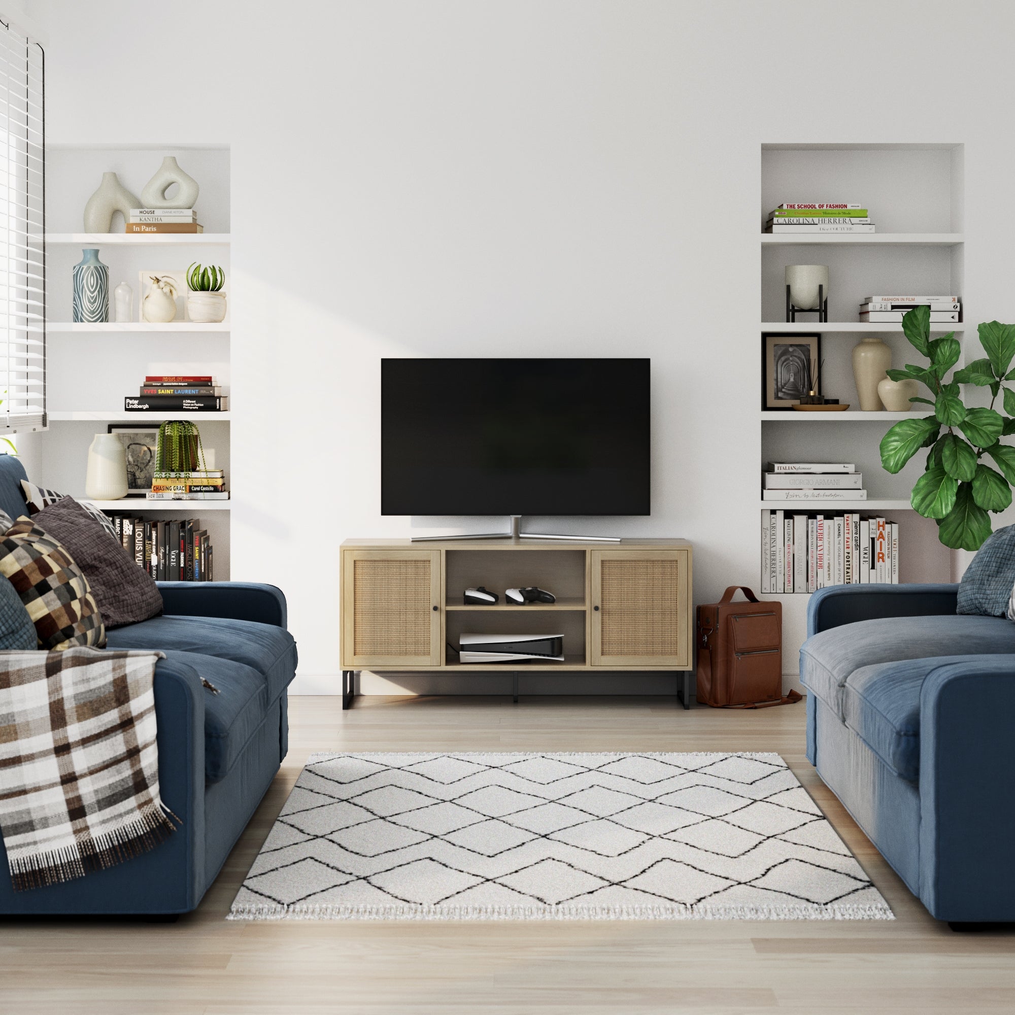 A modern living room with two blue sofas, a patterned rug, shelves with books and decor, a tall green plant, and a TV on the Nathan James Rattan & Wood 2-Door TV Cabinet in Light Oak near a window with blinds letting in natural light.
