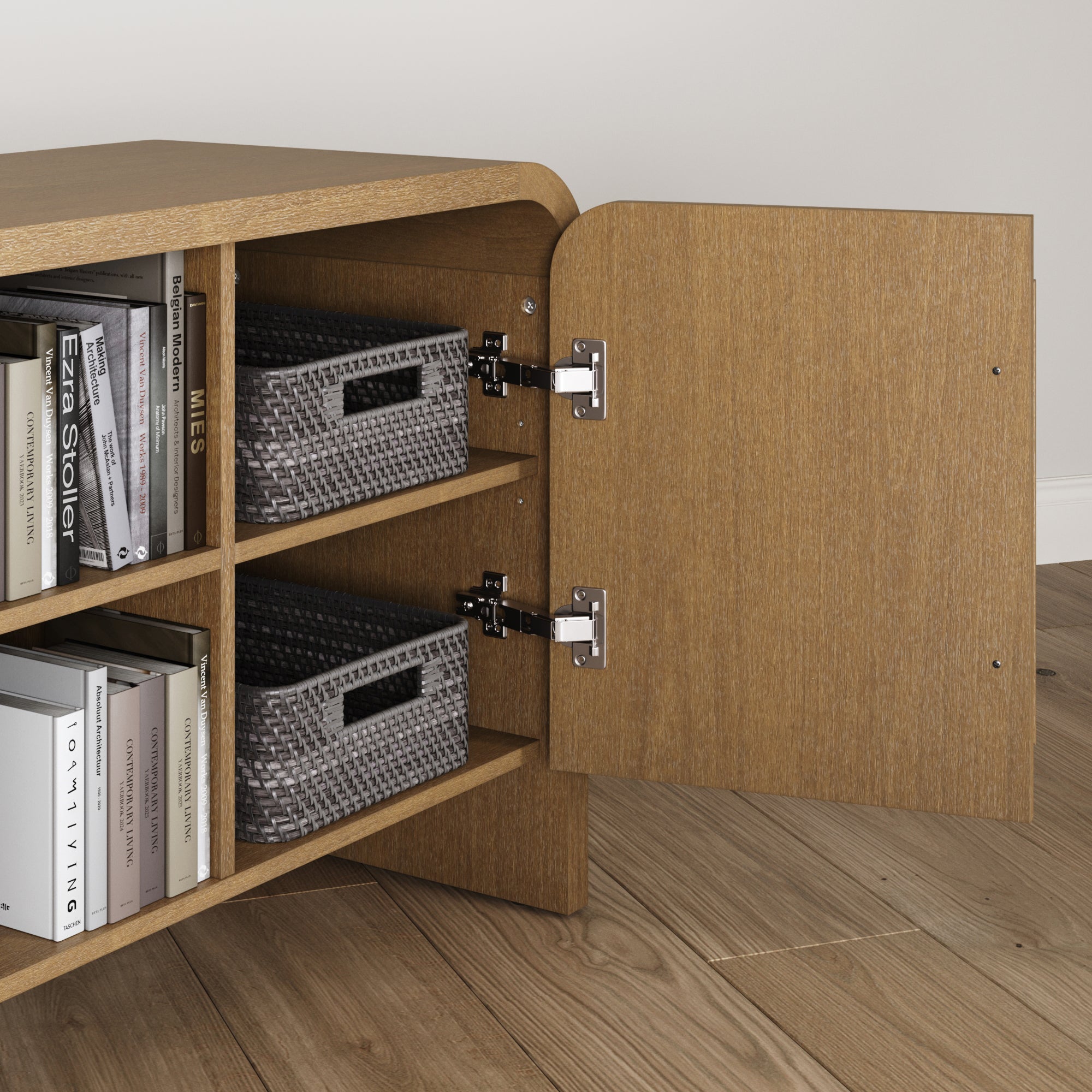 A wooden cabinet with an open door reveals shelves holding woven gray baskets and neatly arranged books. The cabinet sits on light brown wooden flooring against a white wall.