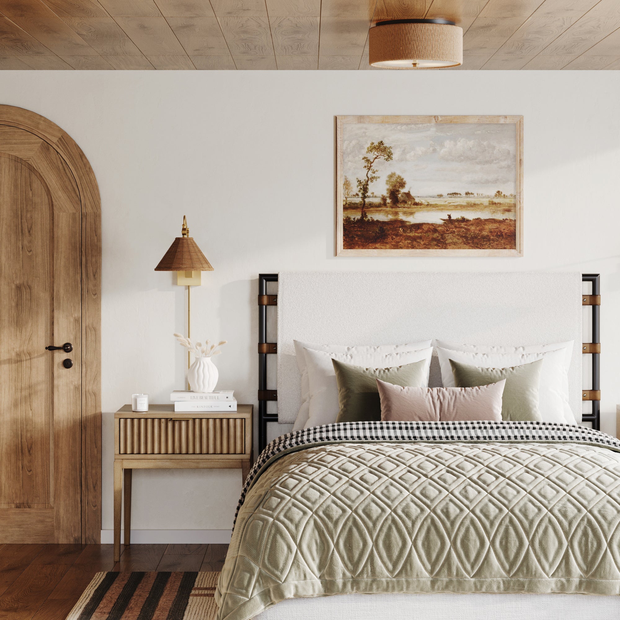 A cozy bedroom features a wooden ceiling, arched door, and a bed with textured bedding. The Nathan James Bohemian Wood Nightstand with Drawer in light brown holds books, a vase, and lamp. A landscape painting hangs above the bed.